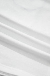 Tissu blanc du t-shirt, texture et plis visibles.