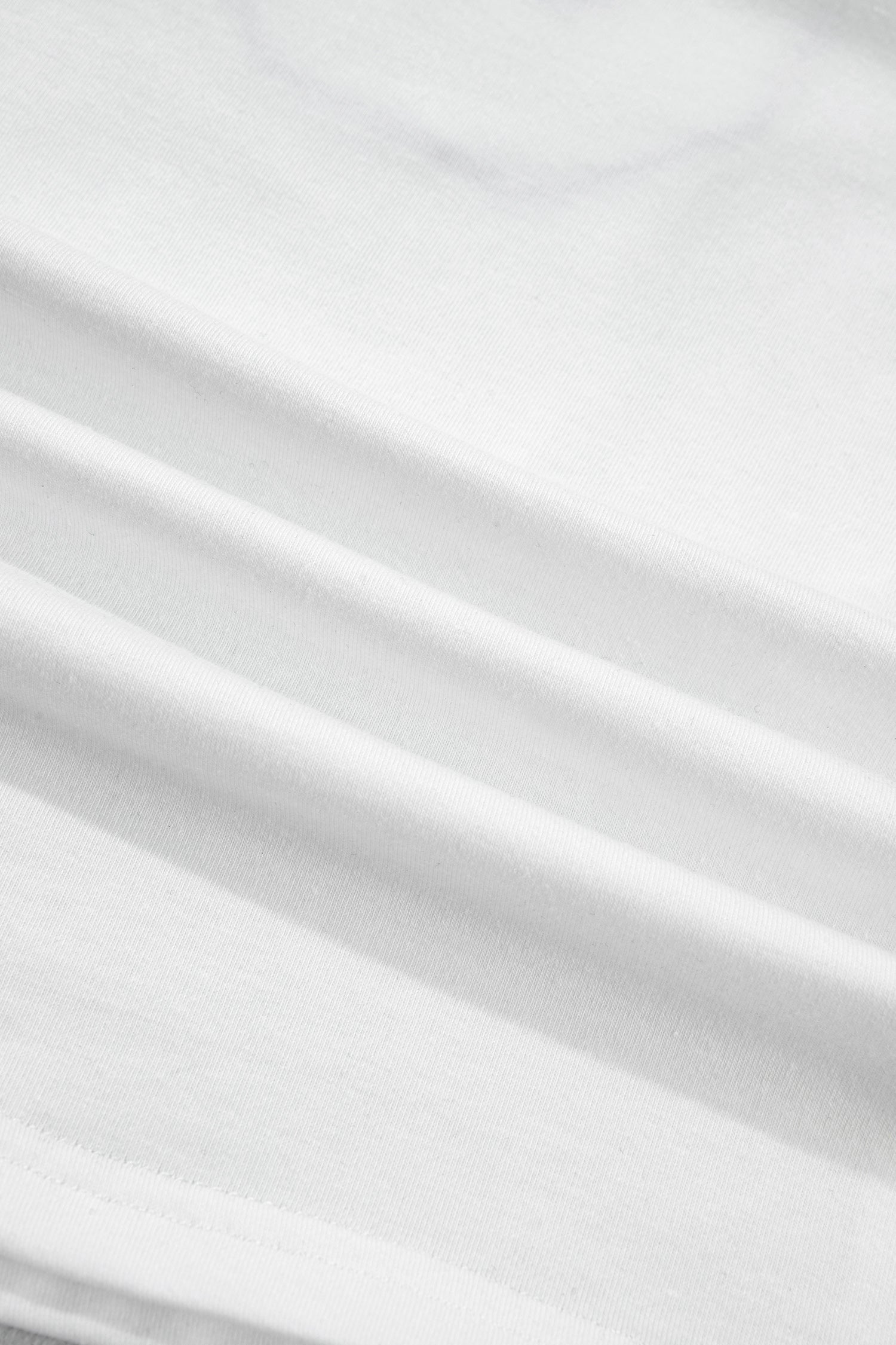 Tissu blanc du t-shirt, texture et plis visibles.