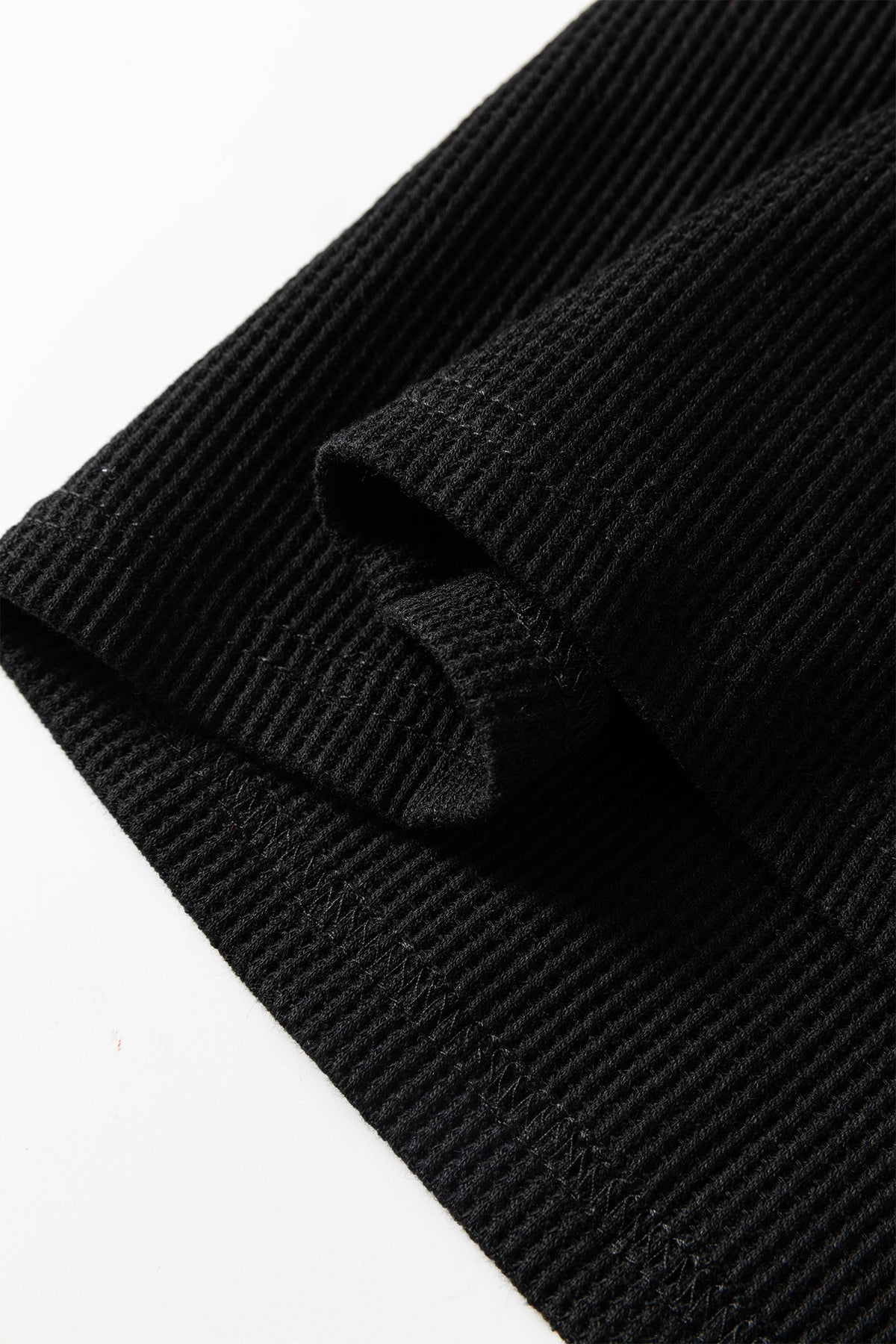 Tissu noir texturé de la robe, ourlet et pli près du col.