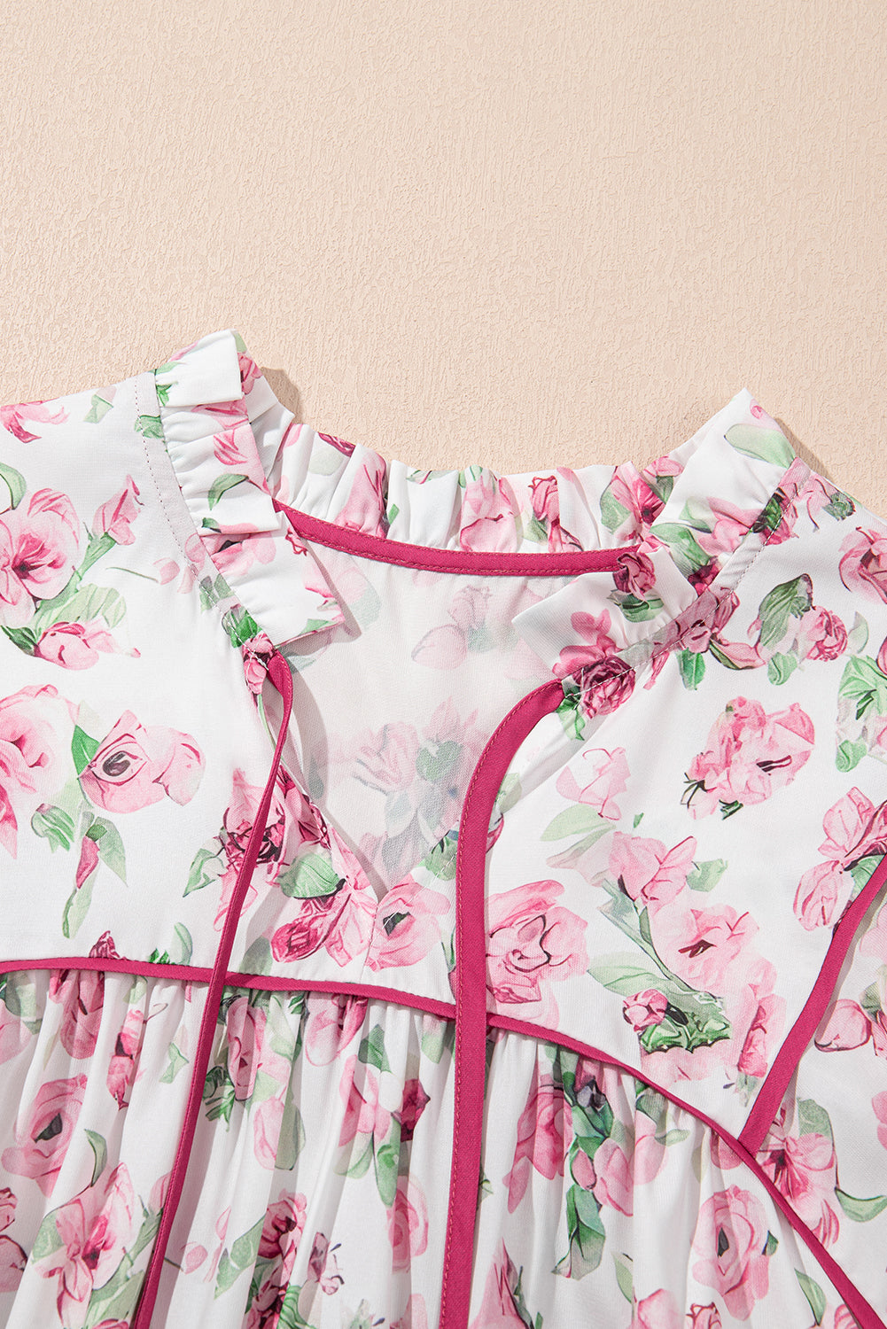 Robe motif floral rose, encolure froncée avec rubans et bord fuchsia