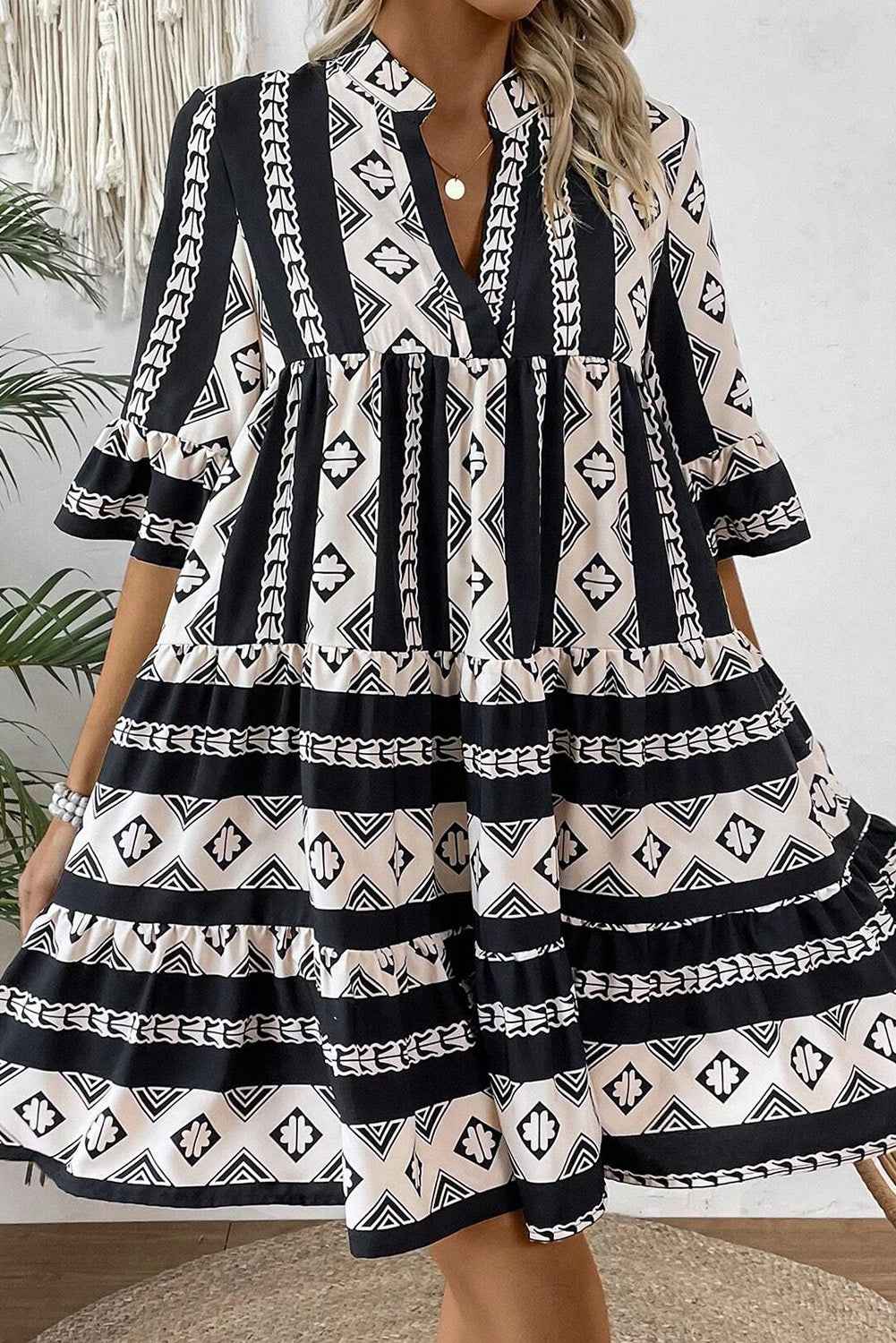 Robe noire motifs géométriques, col V, manches courtes et jupe à volants