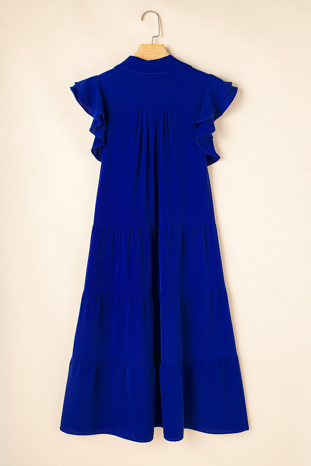 Robe midi bleue sur cintre, dos avec coutures, manches volantées et volants superposés.