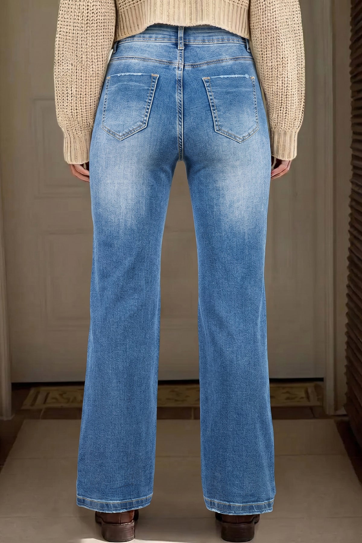 Jean taille haute droit bleu clair, poches arrière, surpiqûres et boutons visibles.