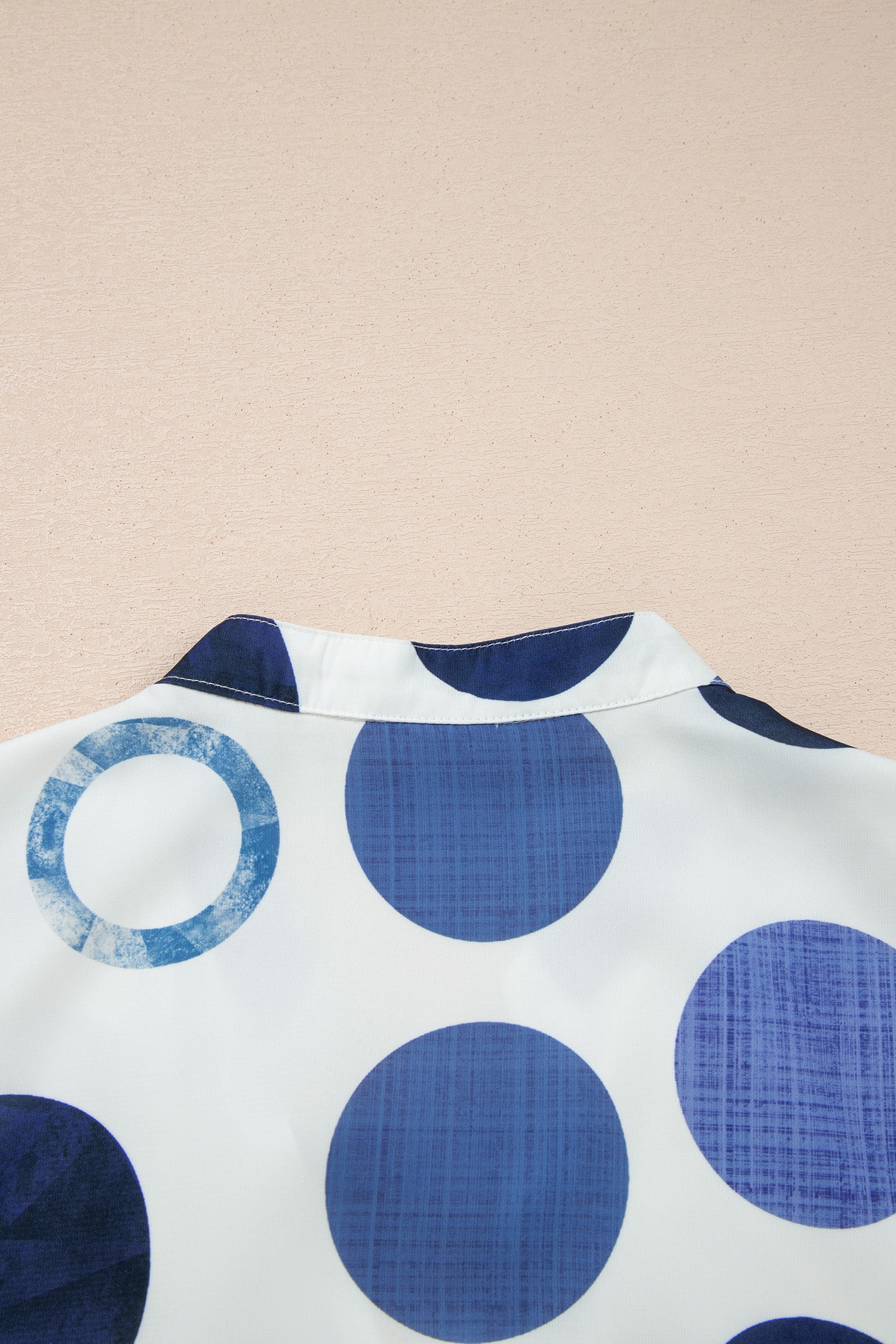 Gros plan sur encolure de la robe blanche à pois bleu