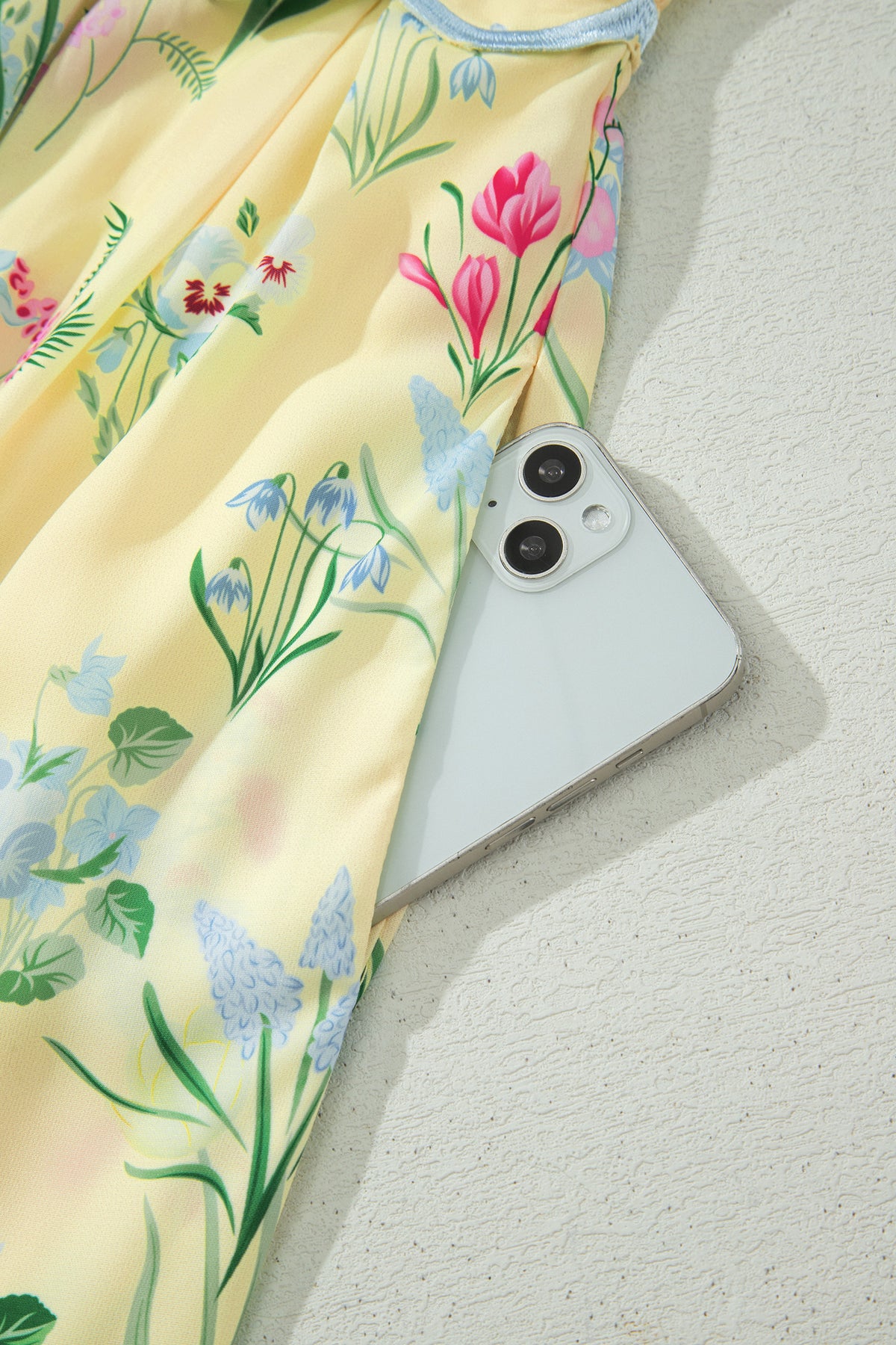 Robe crème à fleurs, bretelles nouées et bordure bleu clair en finition festonnée.