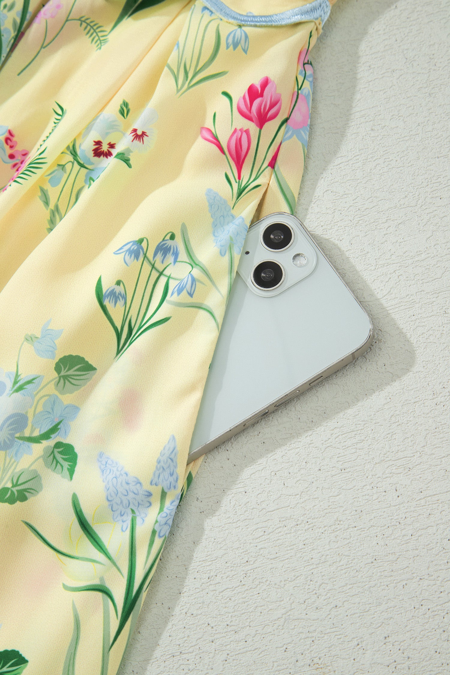 Robe crème à fleurs, bretelles nouées et bordure bleu clair en finition festonnée.