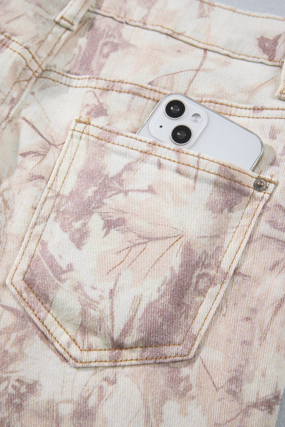 Jean large femme motif camouflage rose clair, poche avant et surpiqûres visibles.