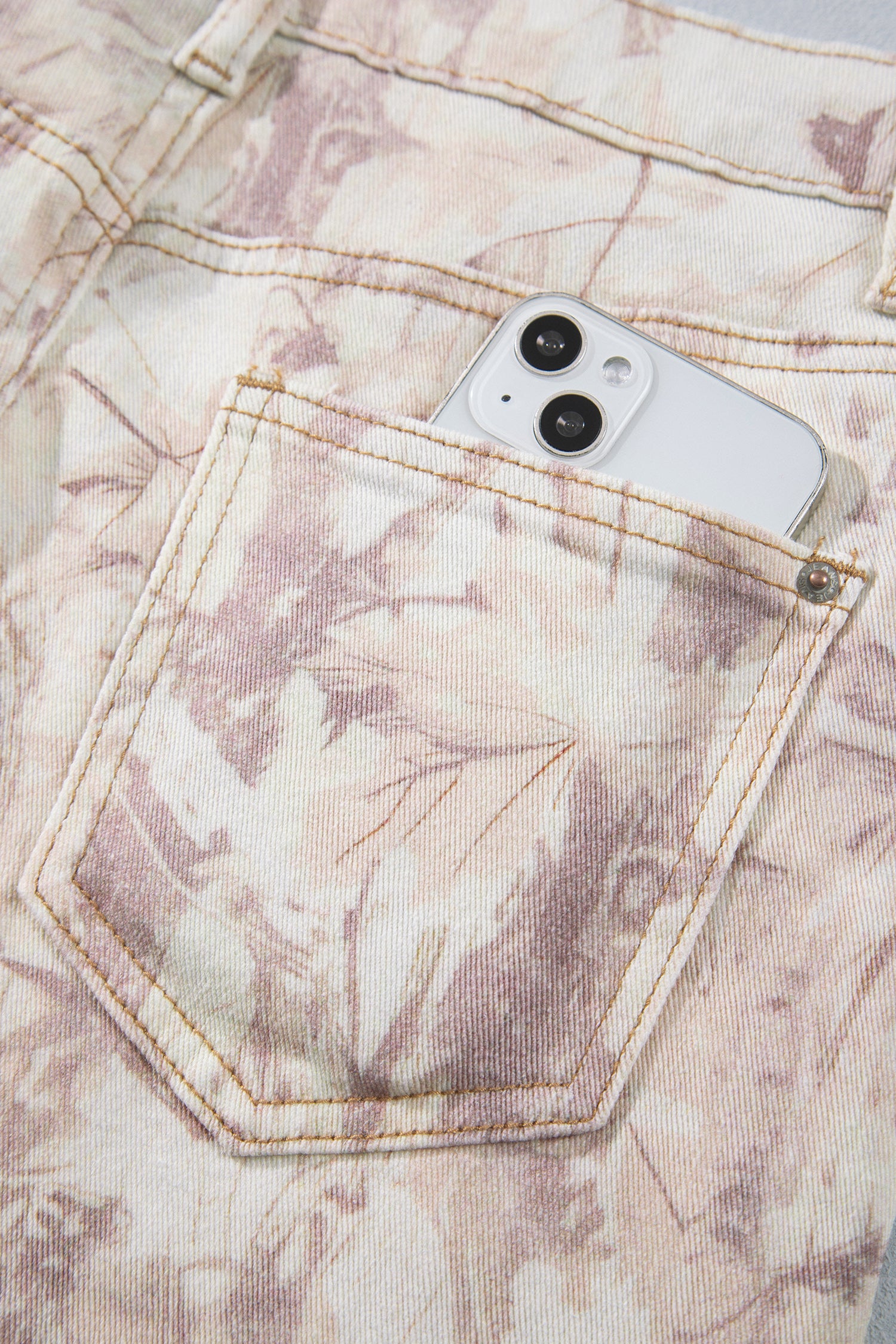 Jean large femme motif camouflage rose clair, poche avant et surpiqûres visibles.