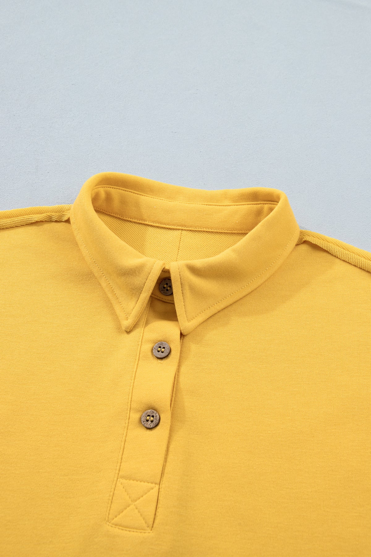 Polo jaune de l’ensemble pour femme : col avec patte boutonnée, empiècement en triangle.