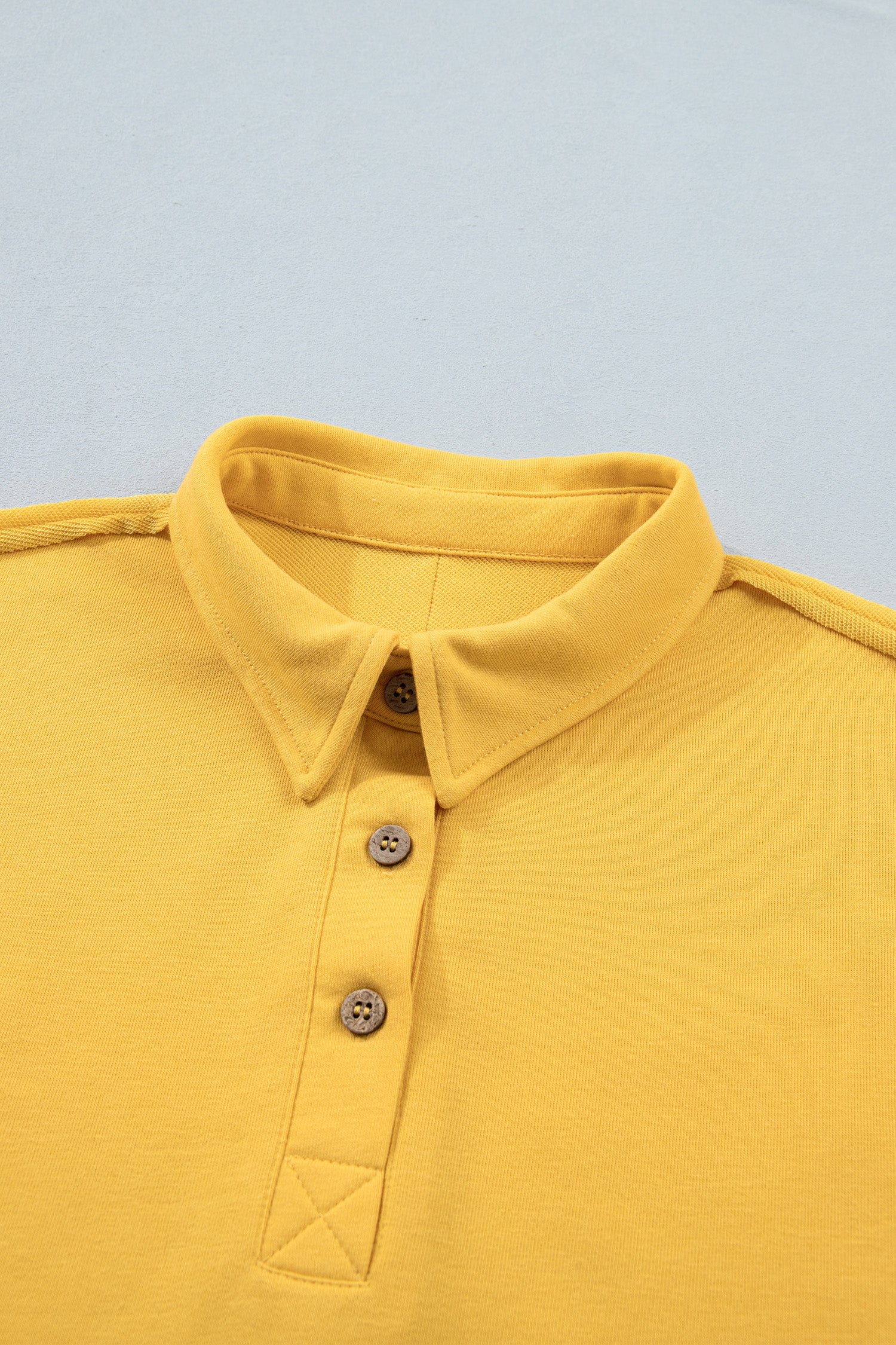 Polo jaune de l’ensemble pour femme : col avec patte boutonnée, empiècement en triangle.