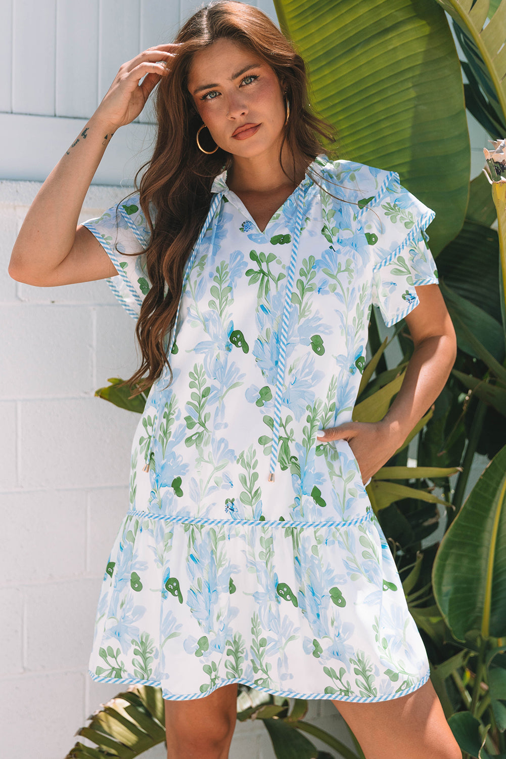 Robe courte blanche à motifs végétaux bleu clair et verts, manches volantées, col V.