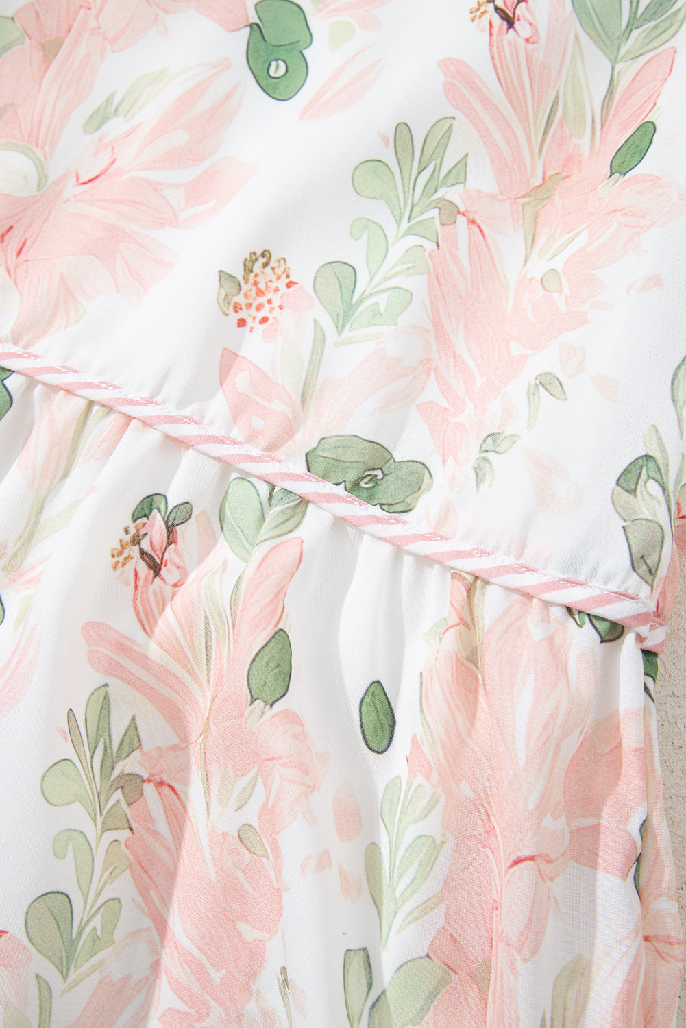 Robe courte rose à fleurs, motif feuillages vert et ruban à rayures sur l’encolure.