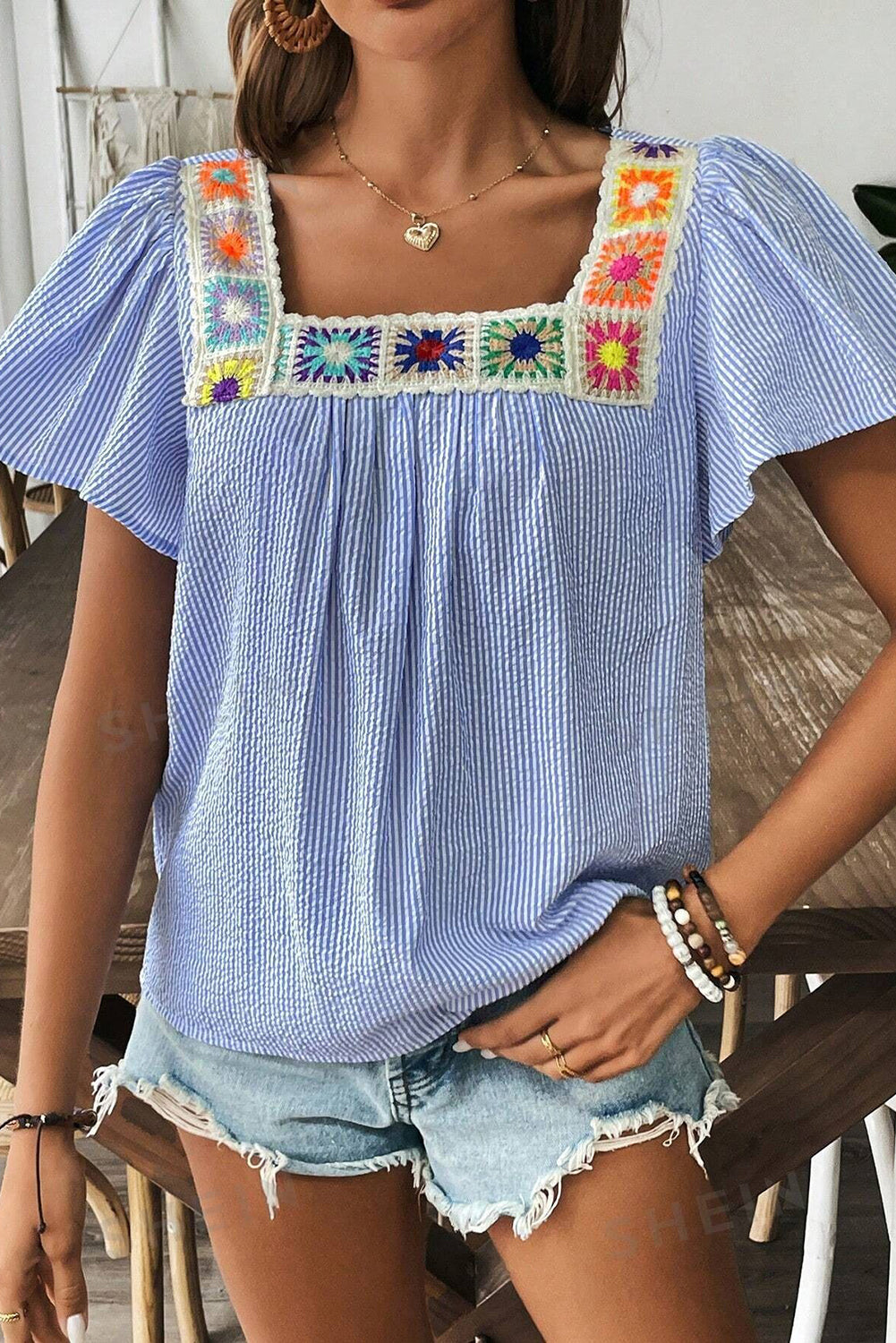 Chemisier bleu ciel à encolure en crochet multicolore, manches courtes à volants