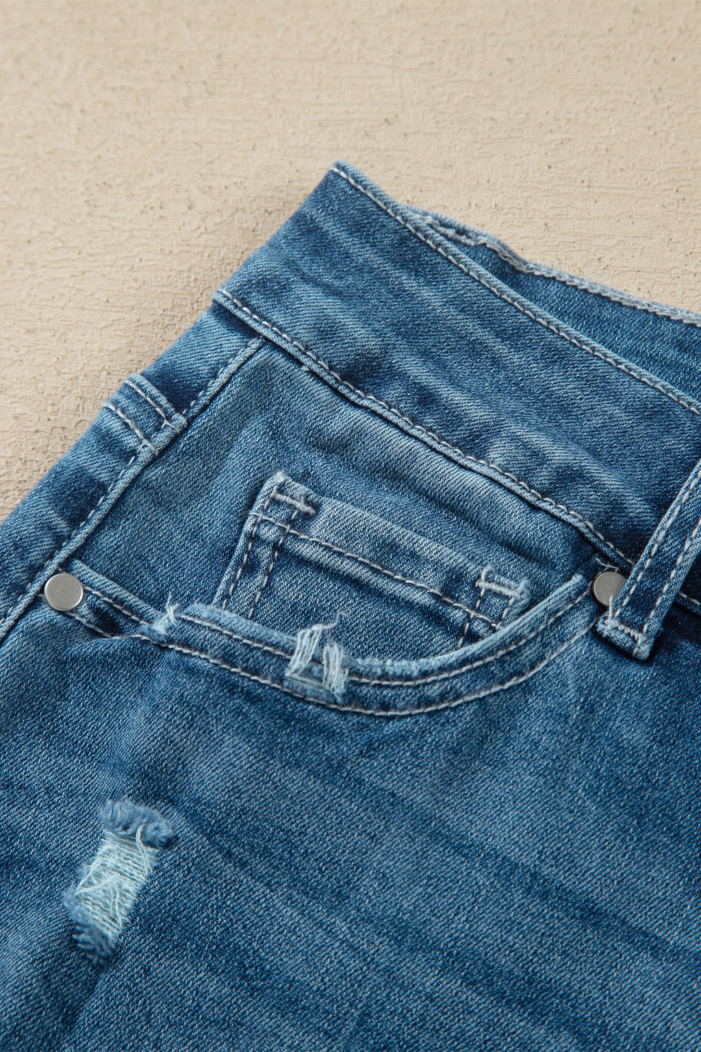 Détail ceinture jean flare taille haute bleu moyen, passants et bouton de fermeture.