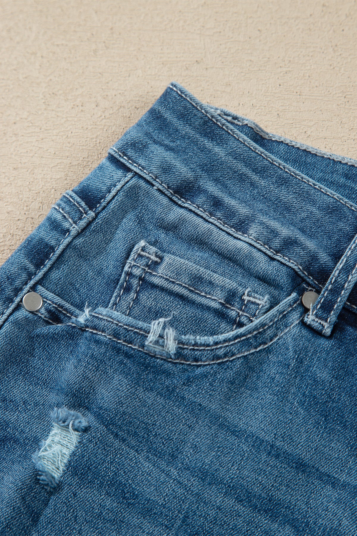 Détail ceinture jean flare taille haute bleu moyen, passants et bouton de fermeture.