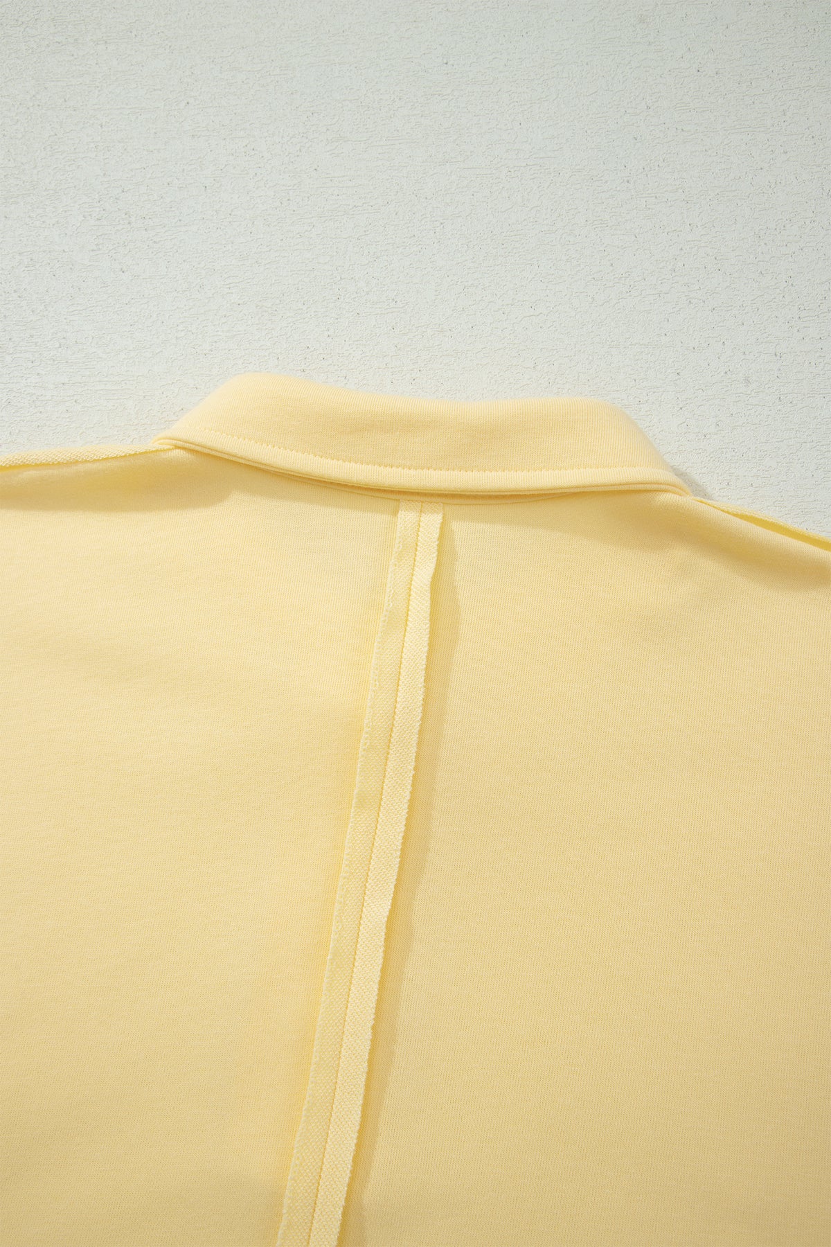 Dos du polo jaune crème avec ouverture/fente centrale et ourlet
