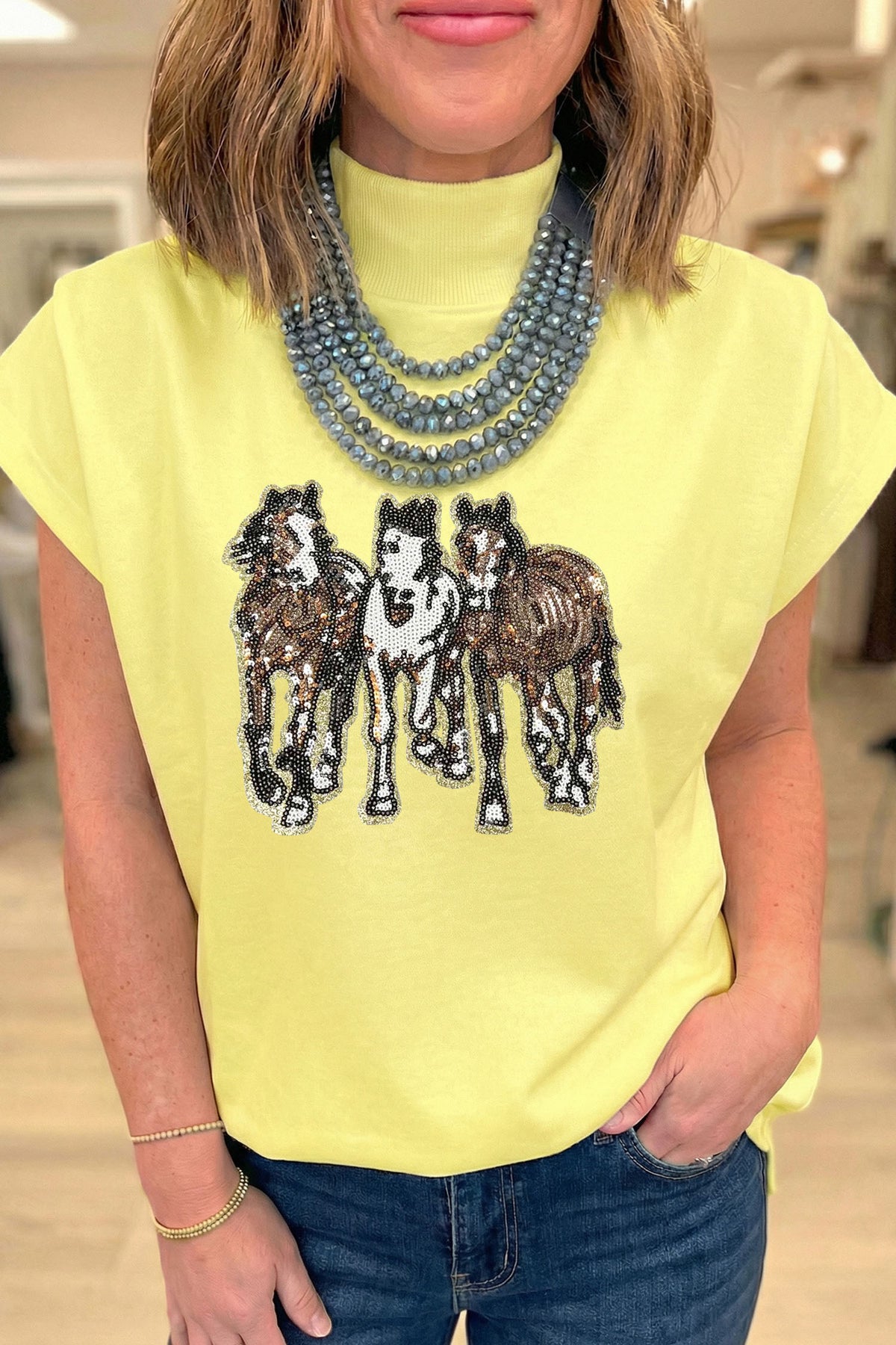 Tunique femme jaune sans manches, col montant, motif de sequins chevaux noirs.