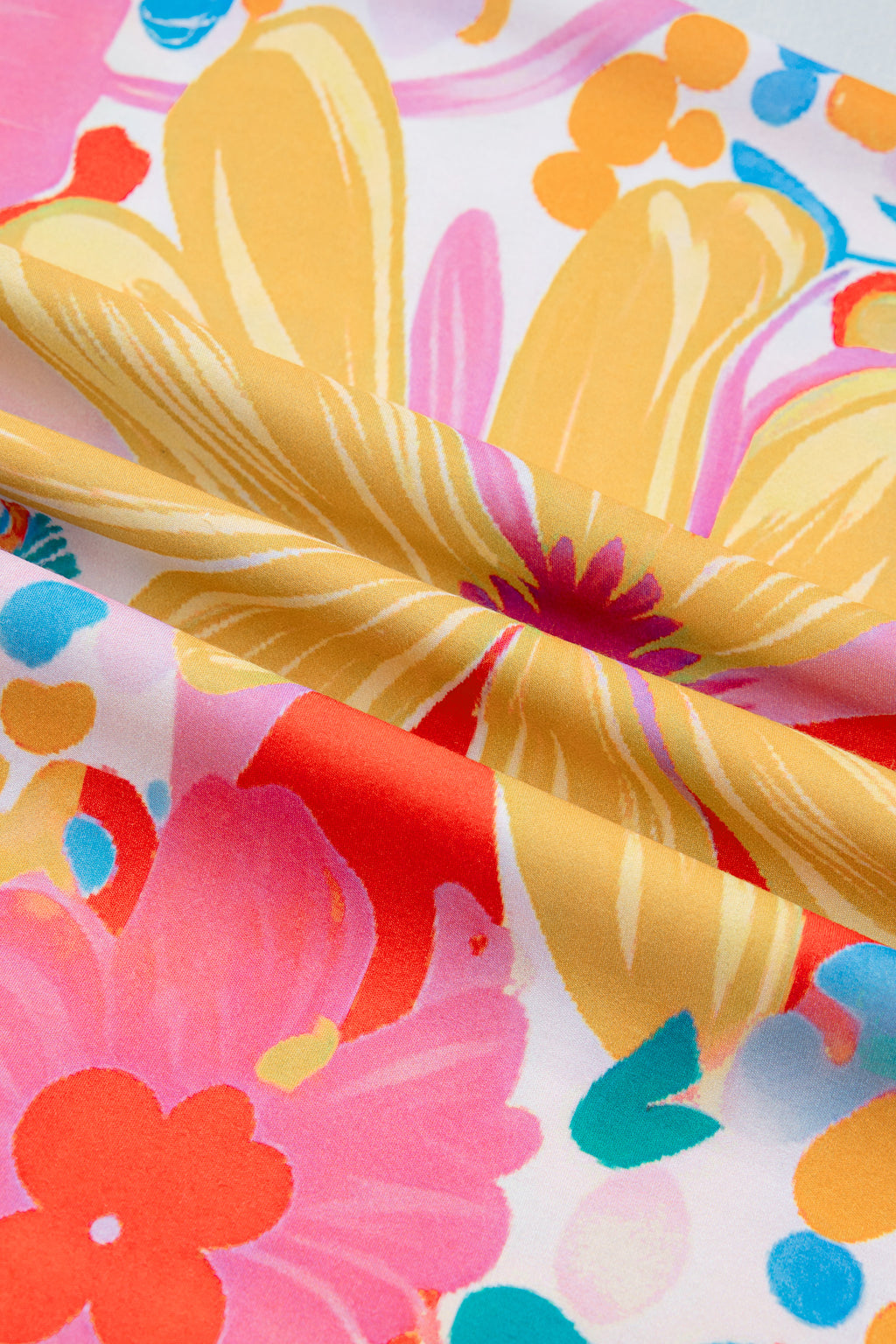 Robe fleurie : gros plan sur le tissu imprimé fleurs et feuillages aux tons rose, orange et bleu.
