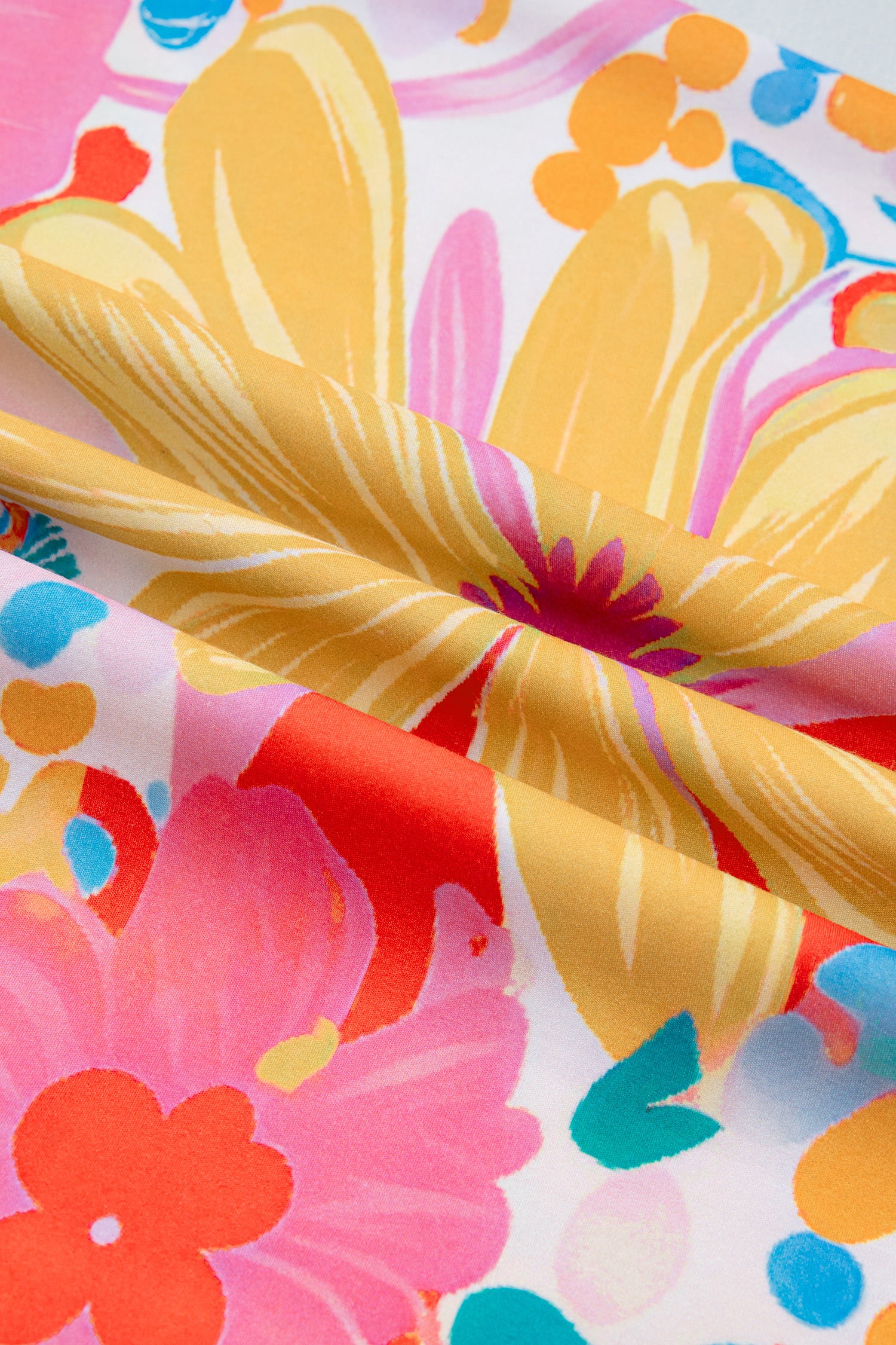 Robe fleurie : gros plan sur le tissu imprimé fleurs et feuillages aux tons rose, orange et bleu.