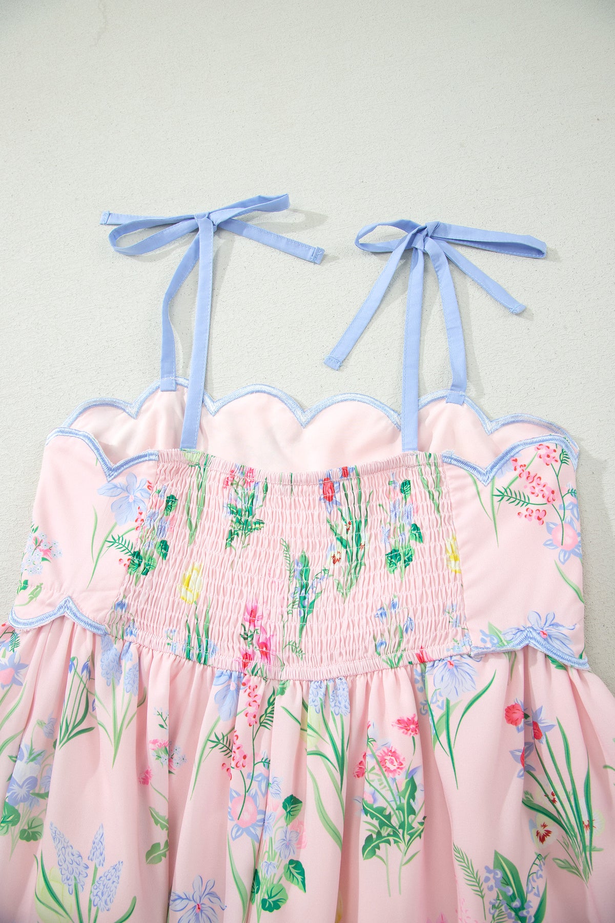 Robe midi rose à bretelles, taille haute, imprimé floral, volants bord bleus.