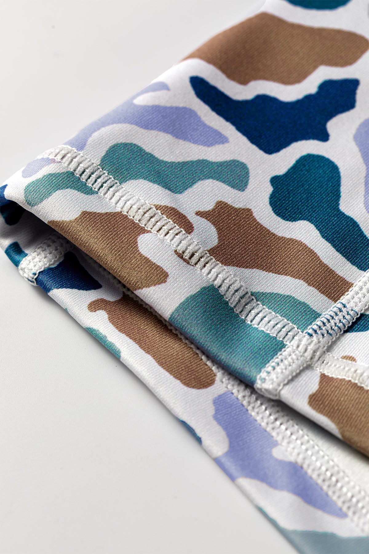 Ourlet du short cycliste imprimé camouflage, élastique blanc et surpiqûres.