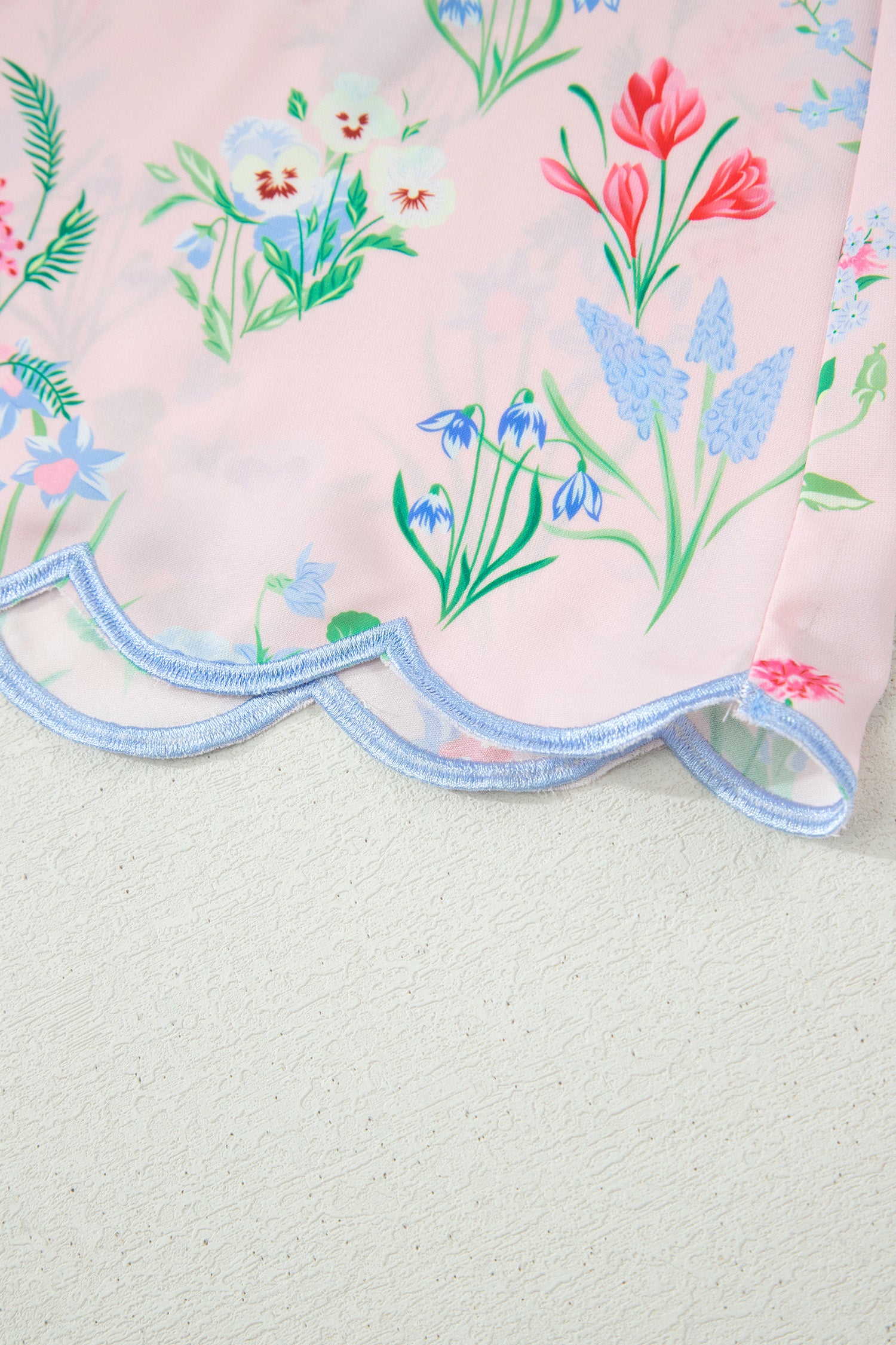Ourlet de robe rose à fleurs, bord festonné bleu clair.