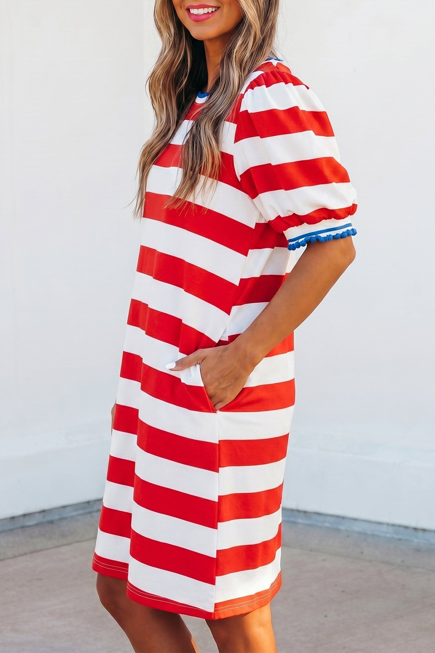 Robe mini rayée rouge et blanche, col rond, manches bouffantes, bordure bleue.