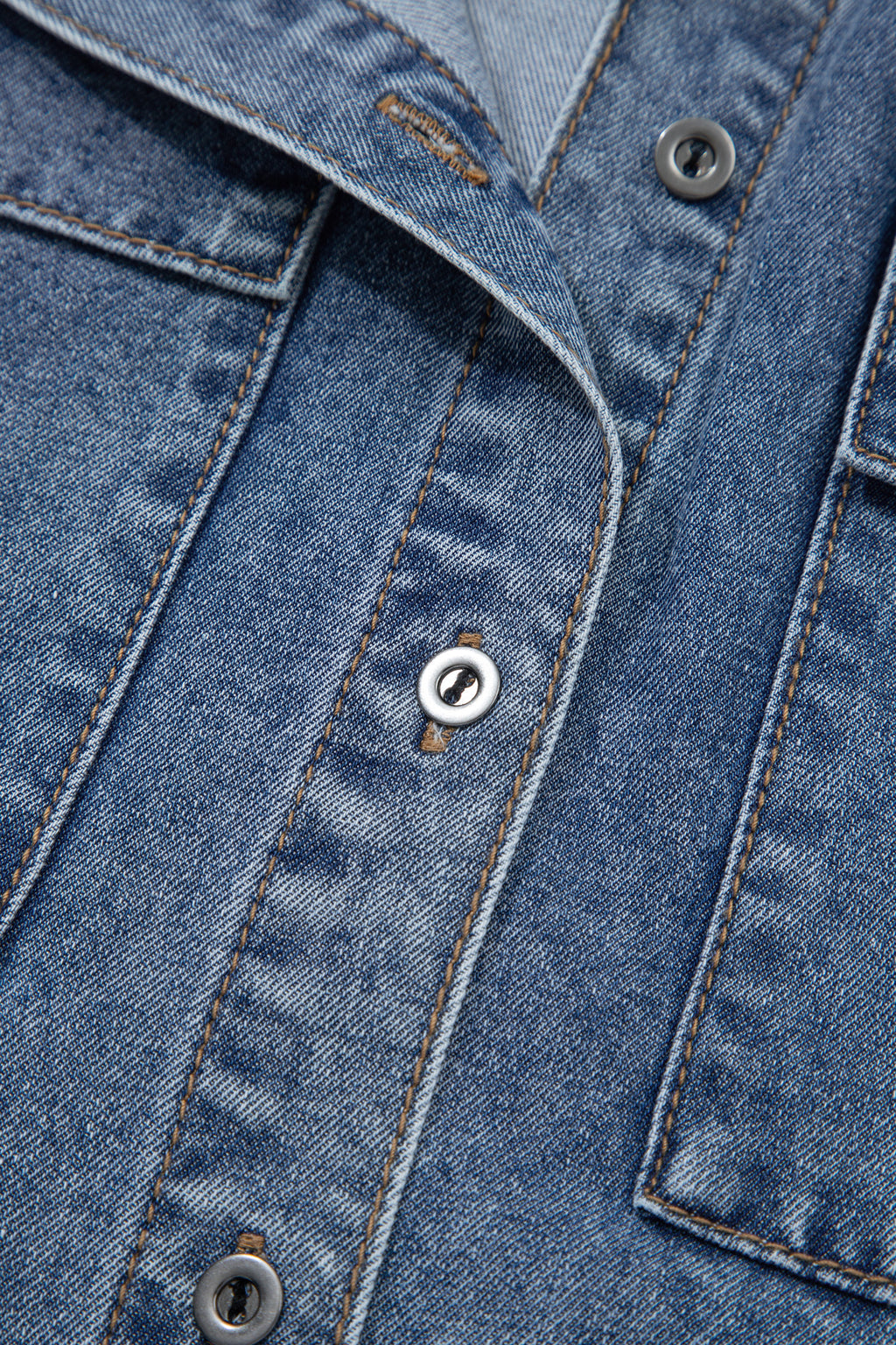 Détails chemisier en jean bleu : boutons pression, surpiqûres et poche poitrine