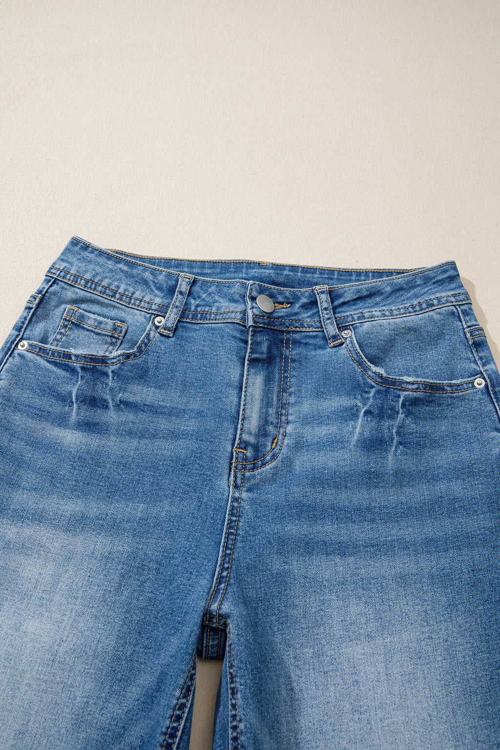 Jean taille haute bleu myosotis, ceinture avec passants et boutons à rivets.