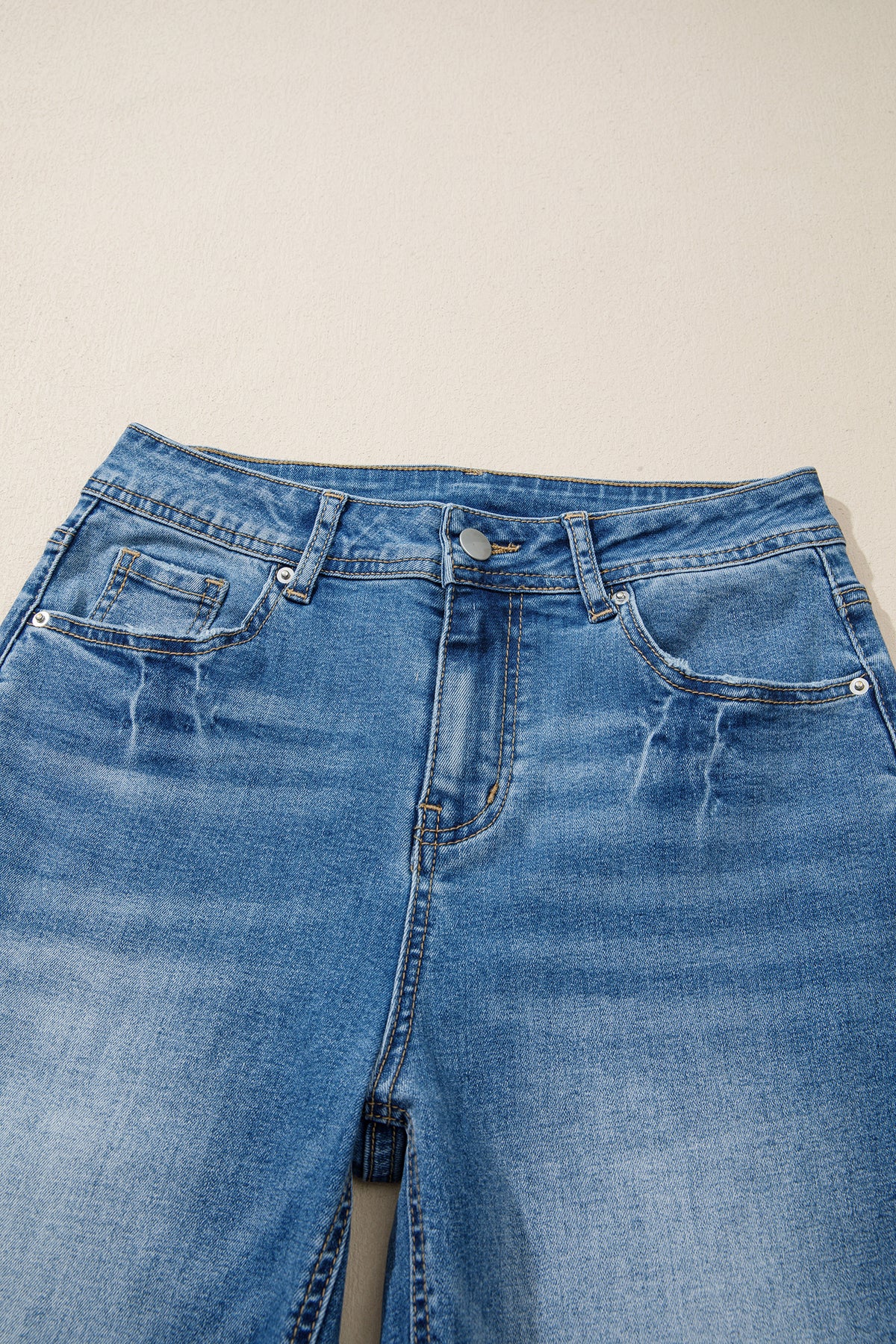 Jean taille haute bleu myosotis, ceinture avec passants et boutons à rivets.