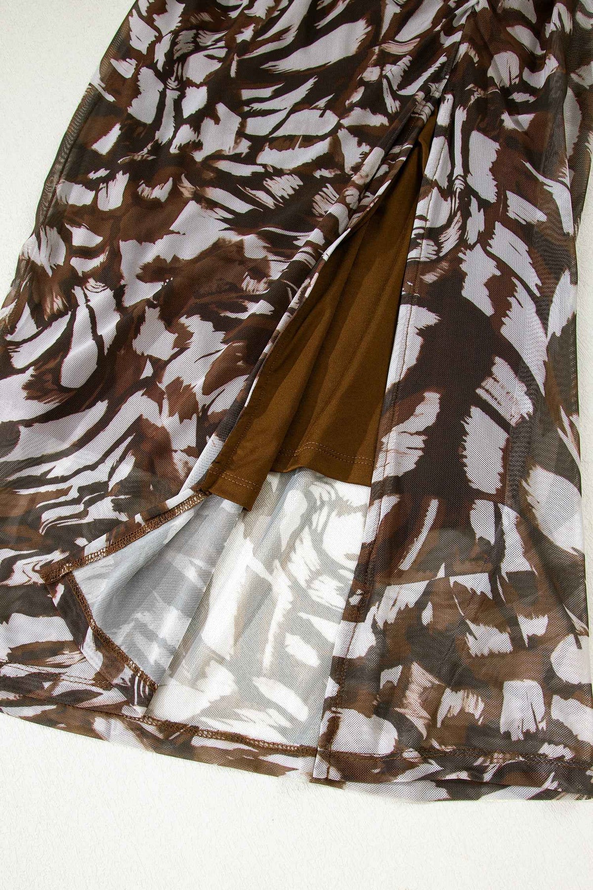 Détail robe midi en résille marron à motif animal, tissu plissé et fente