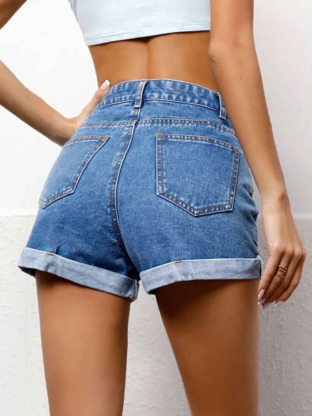 Short en jean taille haute bleu avec poches arrière et revers en bas.