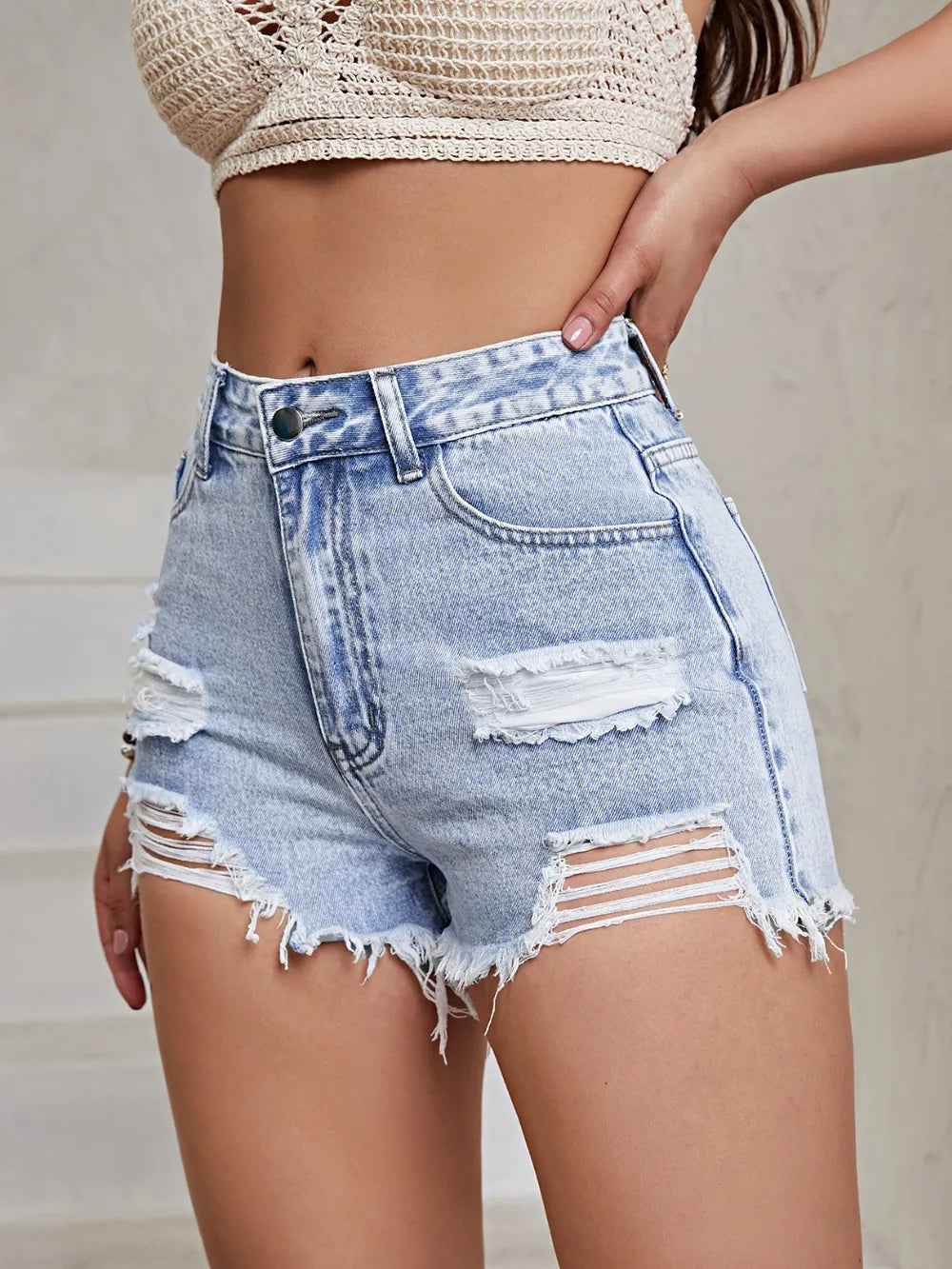Short taille haute en jean bleu ciel usé, empiècements déchirés, franges au bas