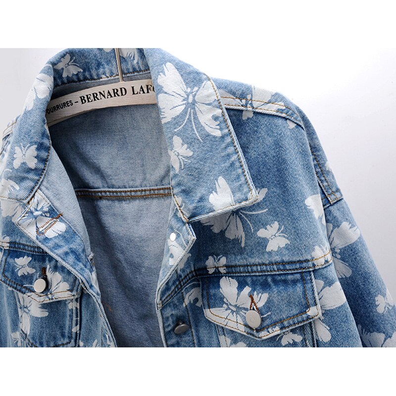 Veste en jean bleue, motif floral blanc, revers, poches poitrine et boutons métal