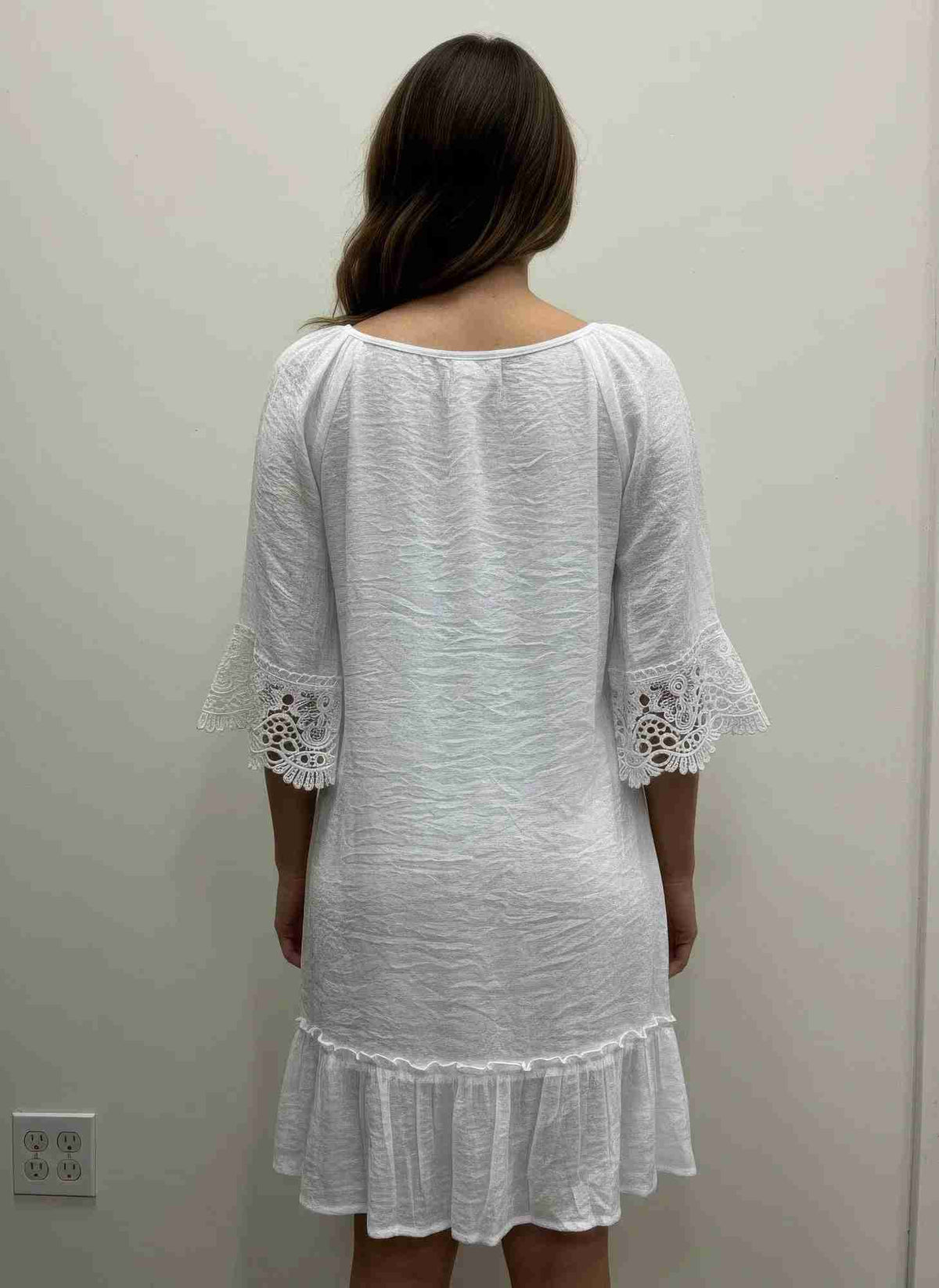 Robe blanche vue de dos, encolure dégagée, dentelle crochet aux manches, volant