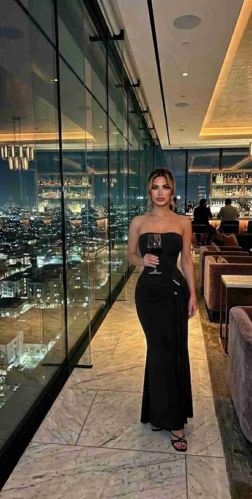 Robe maxi noire drapée style grecque, bustier à fines brides et jupe longue ajustée.