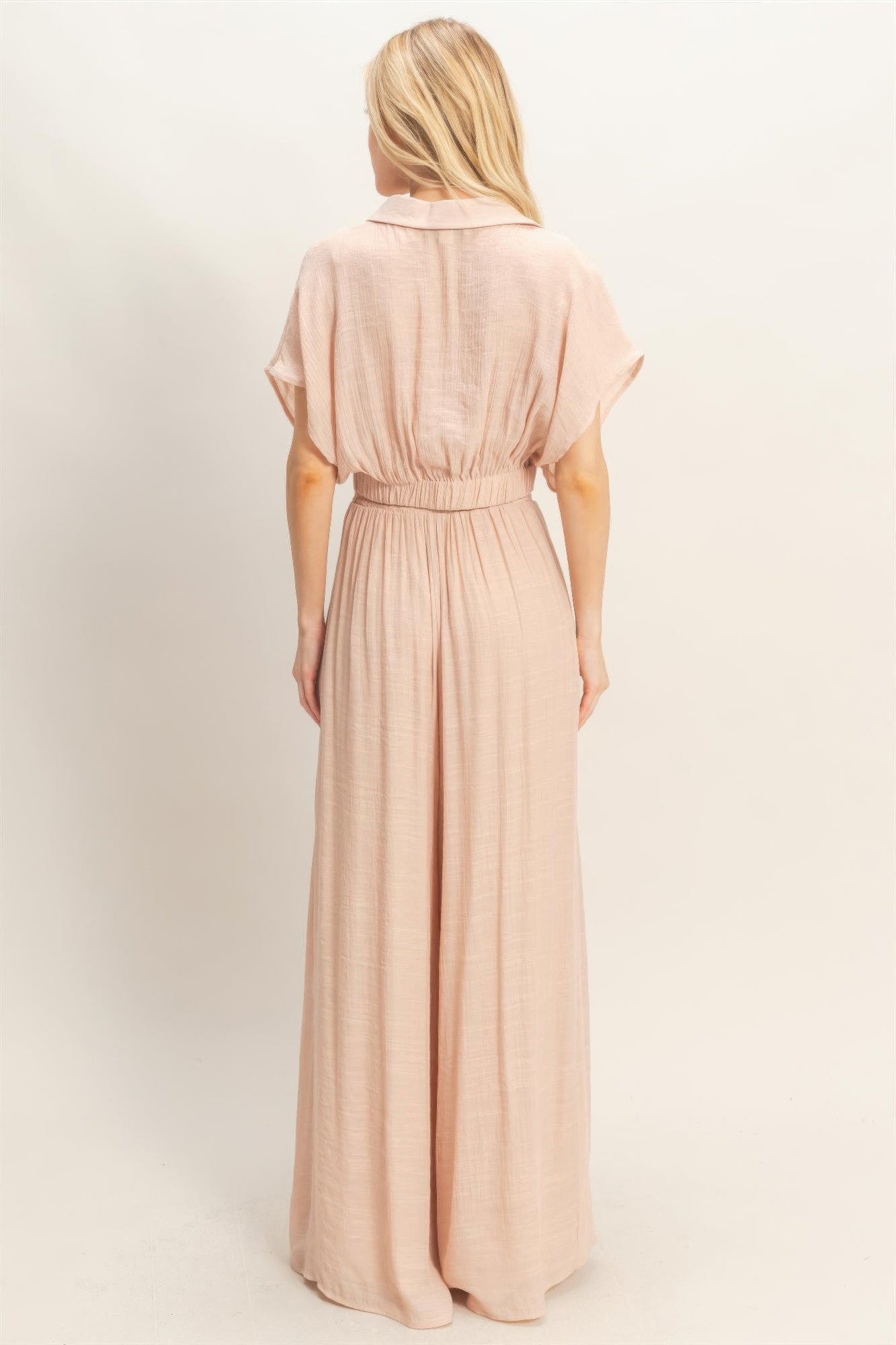 Ensemble deux pièces rosé : haut cache-cœur et pantalon large fluide vu de dos.