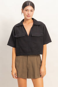 Haut femme en coton noir, col V, manches courtes, poches plaquées devant.