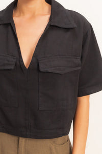 Haut femme en coton noir, col V, poche plaquée poitrine, manches courtes.
