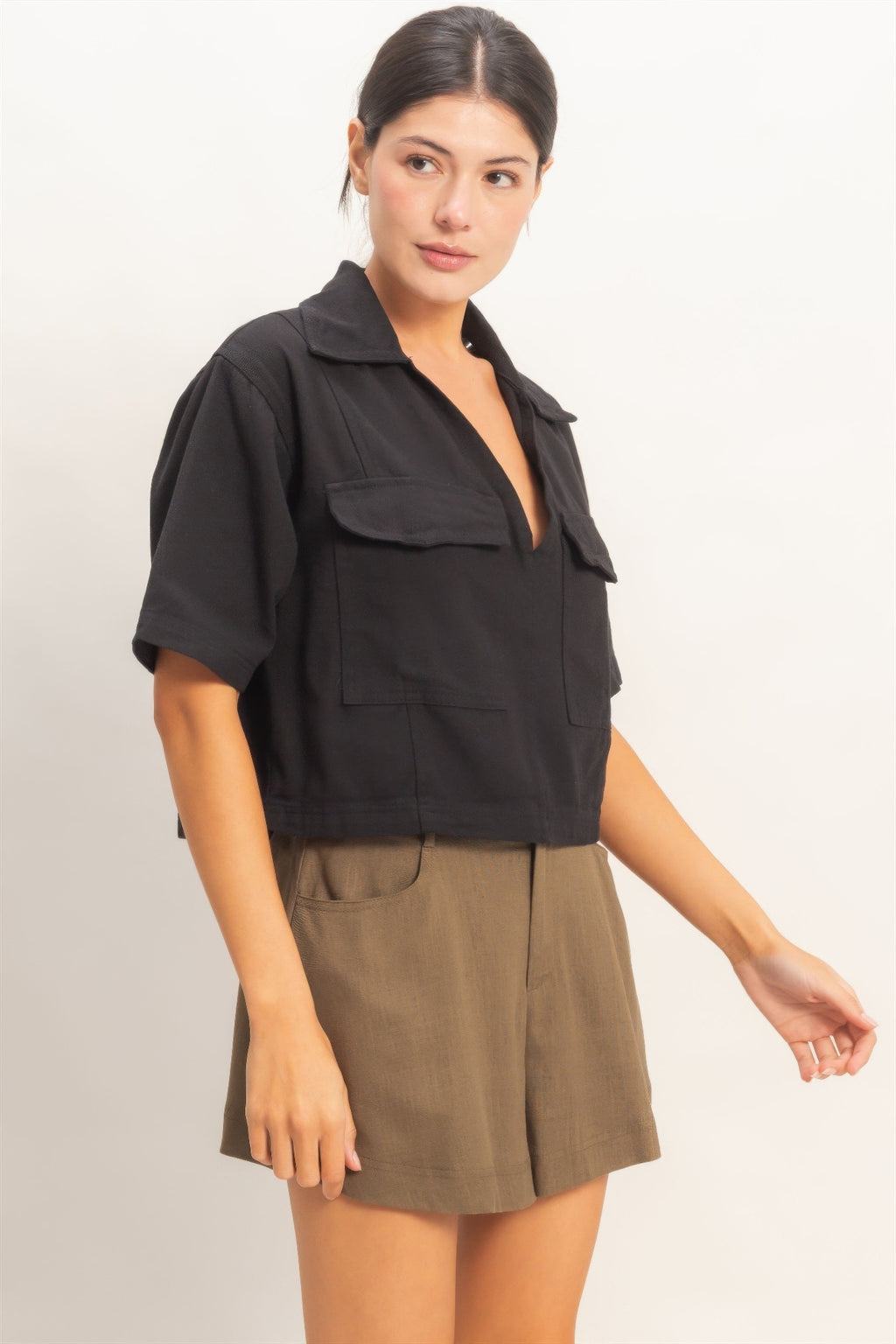 Haut femme en coton noir, col V, manches courtes, poches plaquées sur le devant.