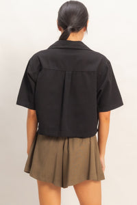Haut femme en coton noir, dos uni, manches courtes, coupe structurée.
