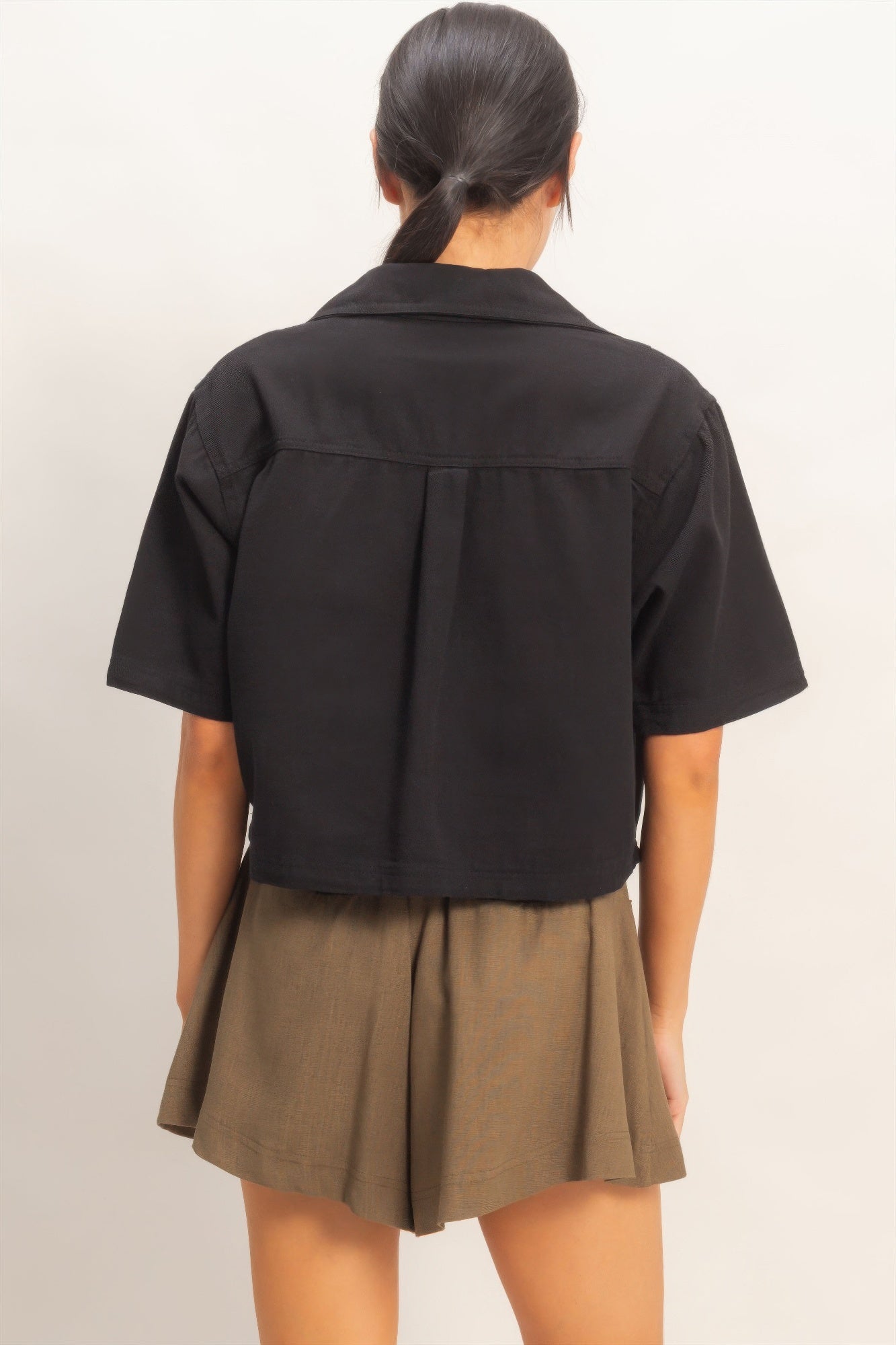 Haut femme en coton noir, dos uni, manches courtes, coupe structurée.