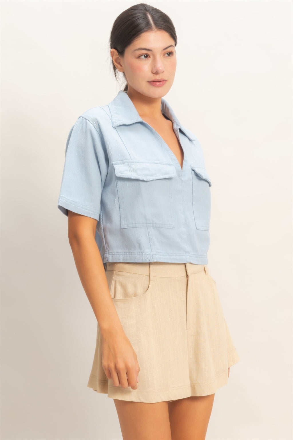 Haut femme en coton bleu ciel, col V, manches courtes, poches plaquées devant.