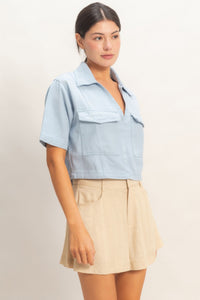 Haut femme en coton bleu ciel, col V, manches courtes, poches plaquées devant.