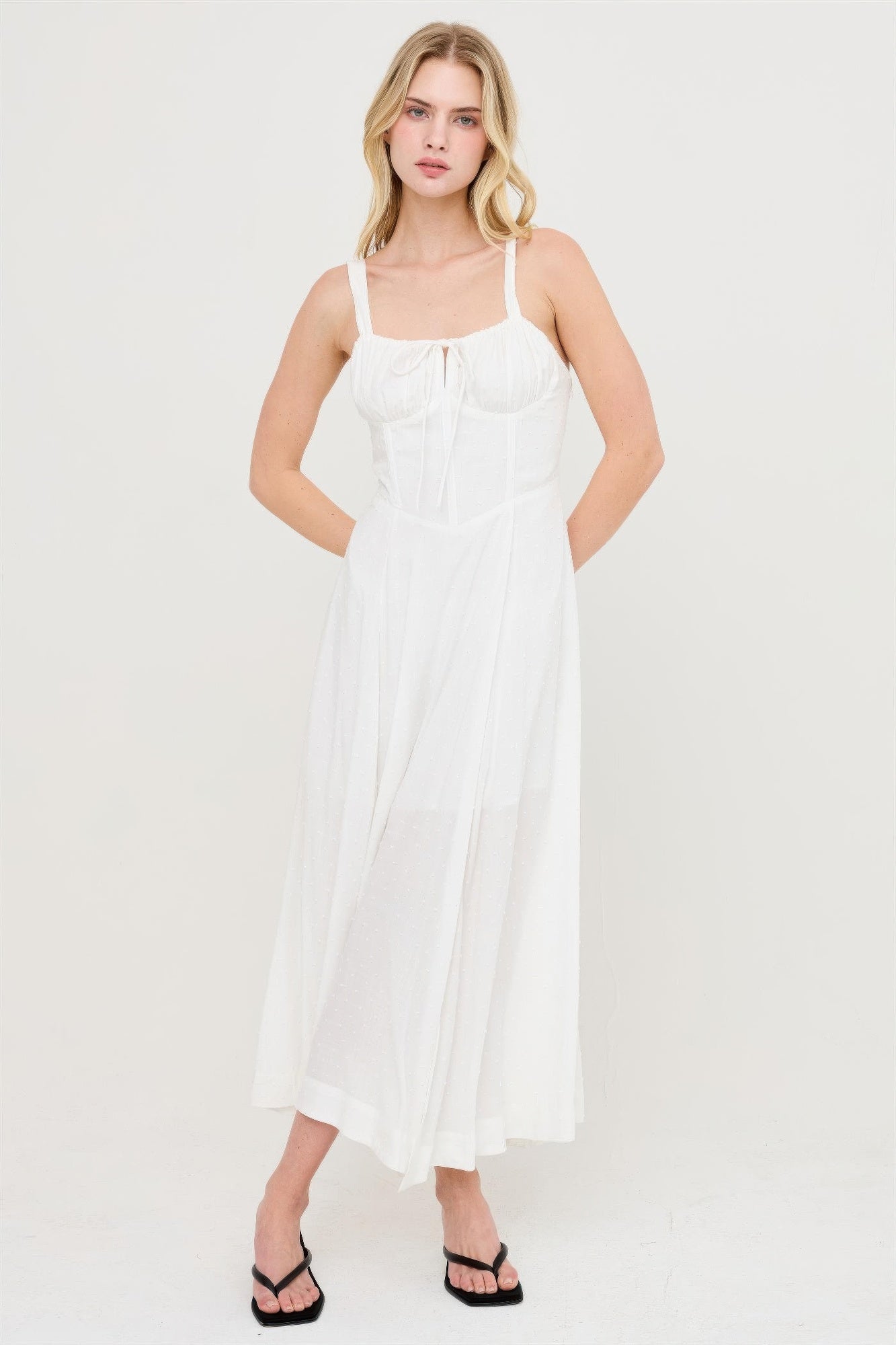 Robe blanche cassé à bretelles fines, corsage smocké, jupe évasée avec fente
