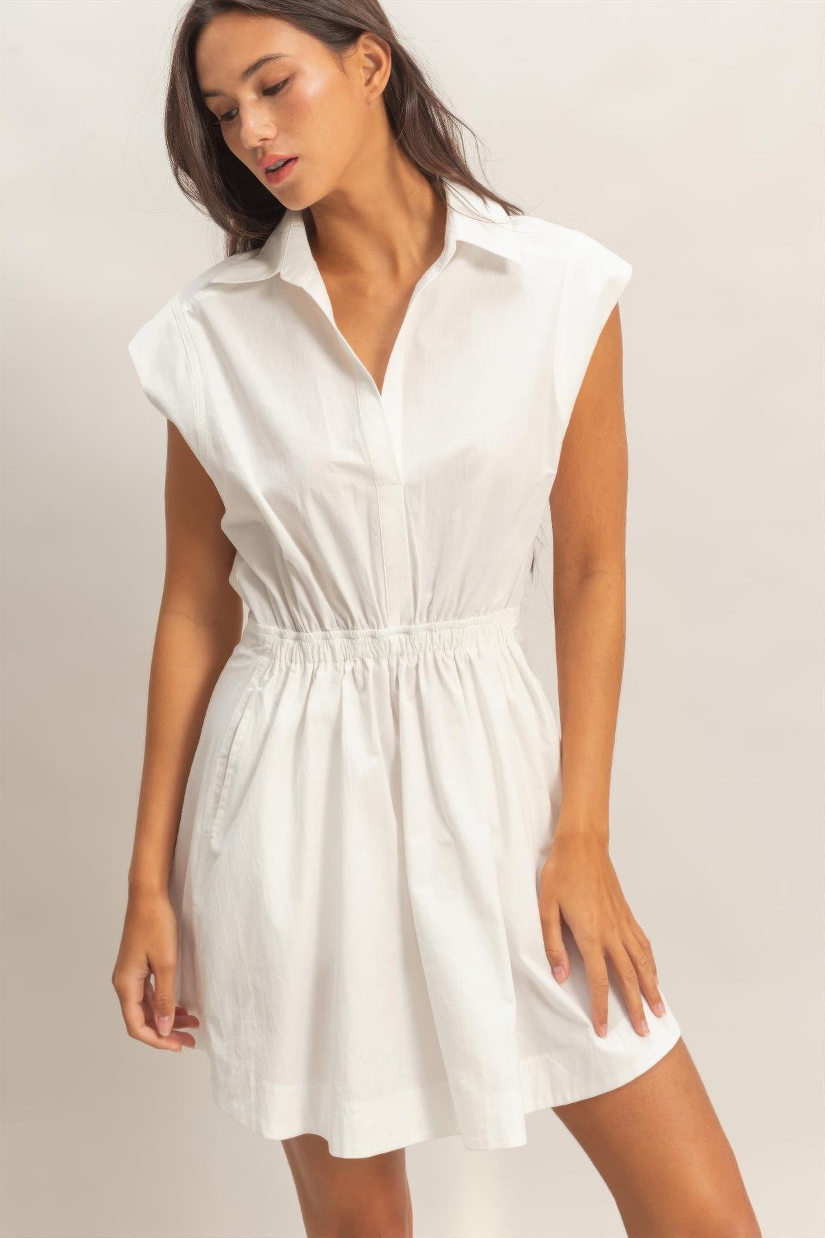 Robe mini sans manches blanc cassé, col chemise, patte boutonnée, taille froncée