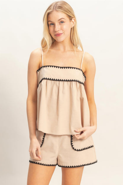 Haut babydoll beige sans manches à bretelles fines, bordure noire et fronces.