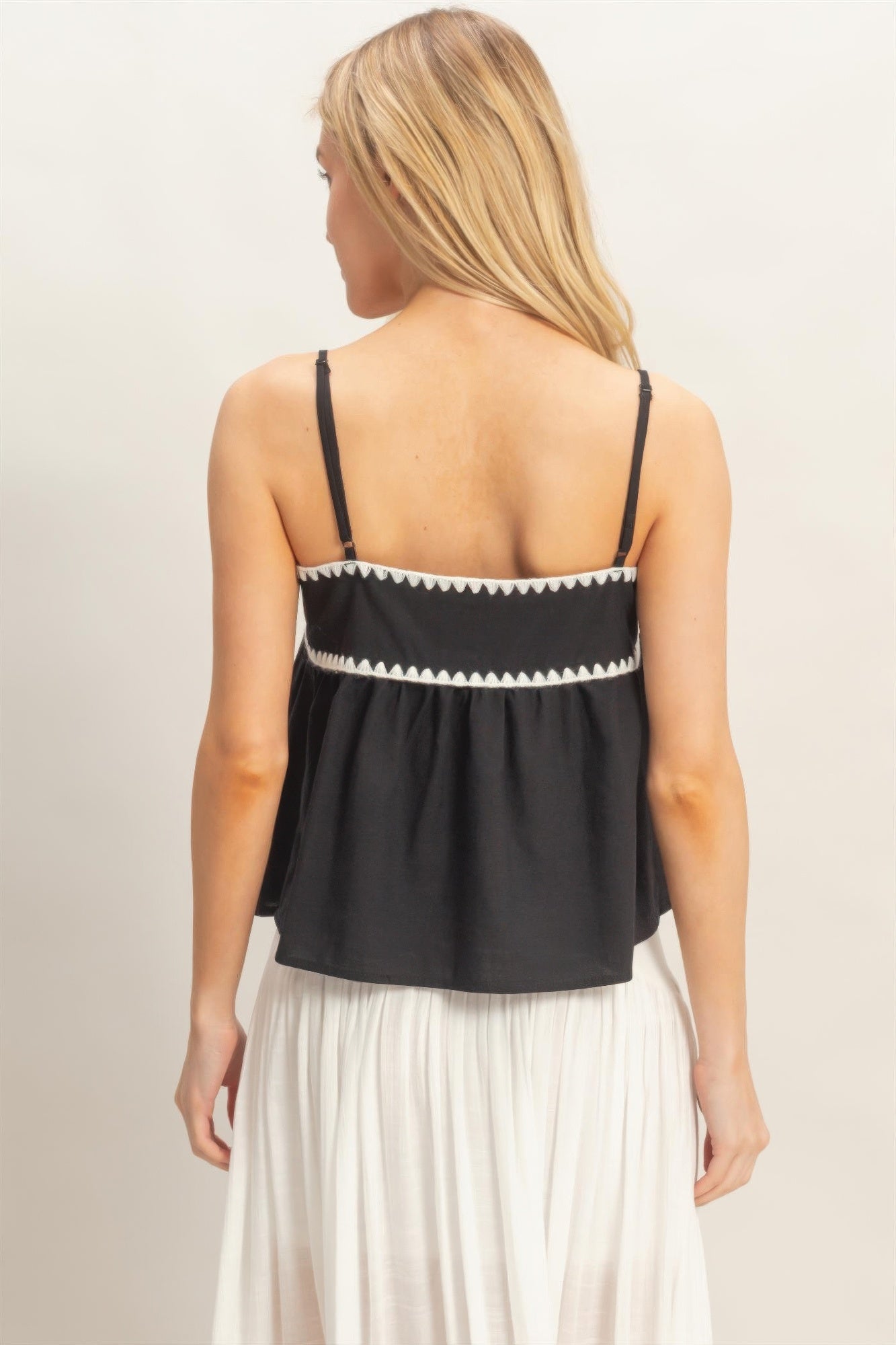 Débardeur babydoll noir à l’arrière, bretelles fines et bordure zigzag contrastée.