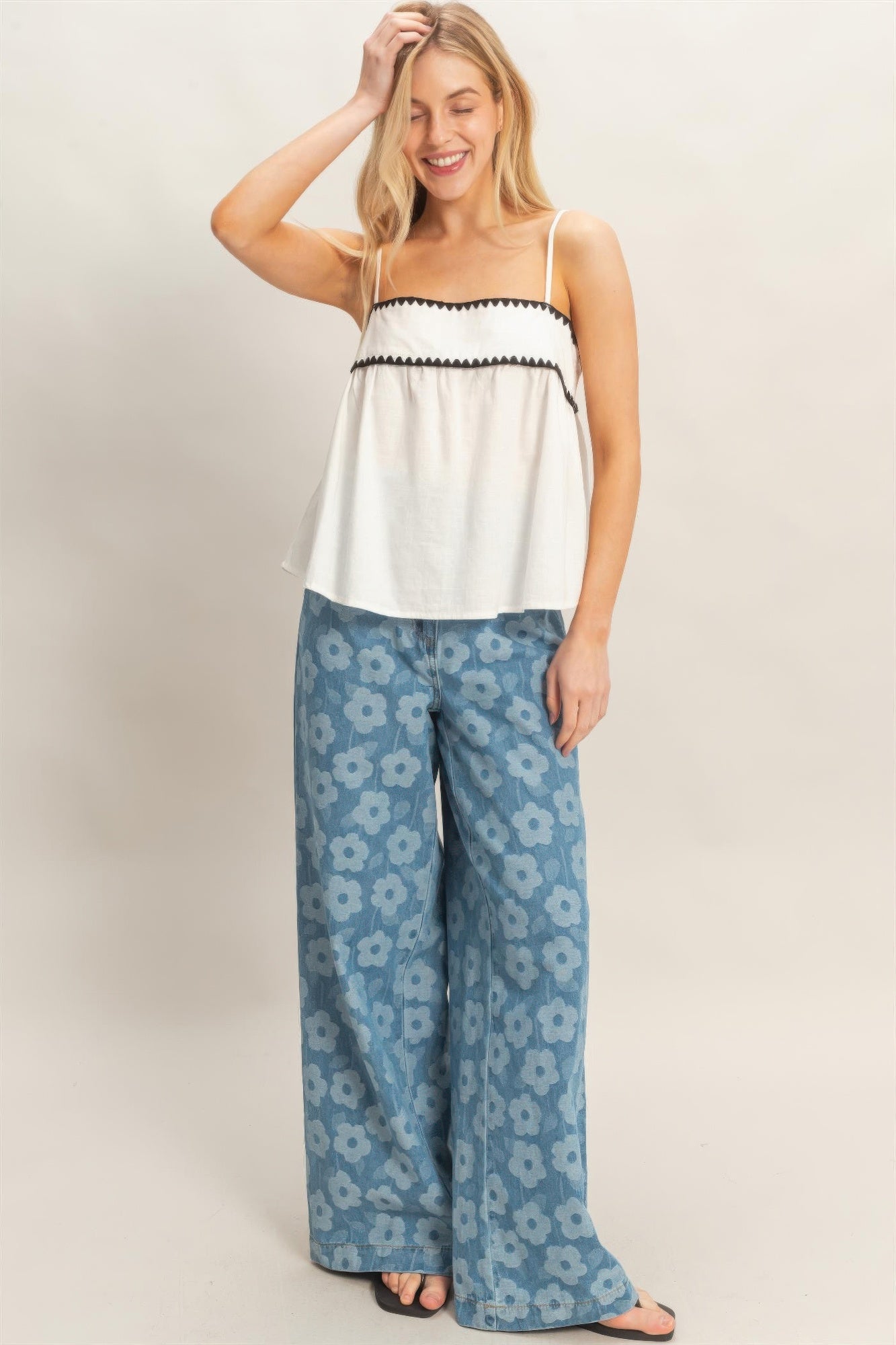 Haut babydoll blanc sans manches à bretelles, bordure noire et empiècement froncé.