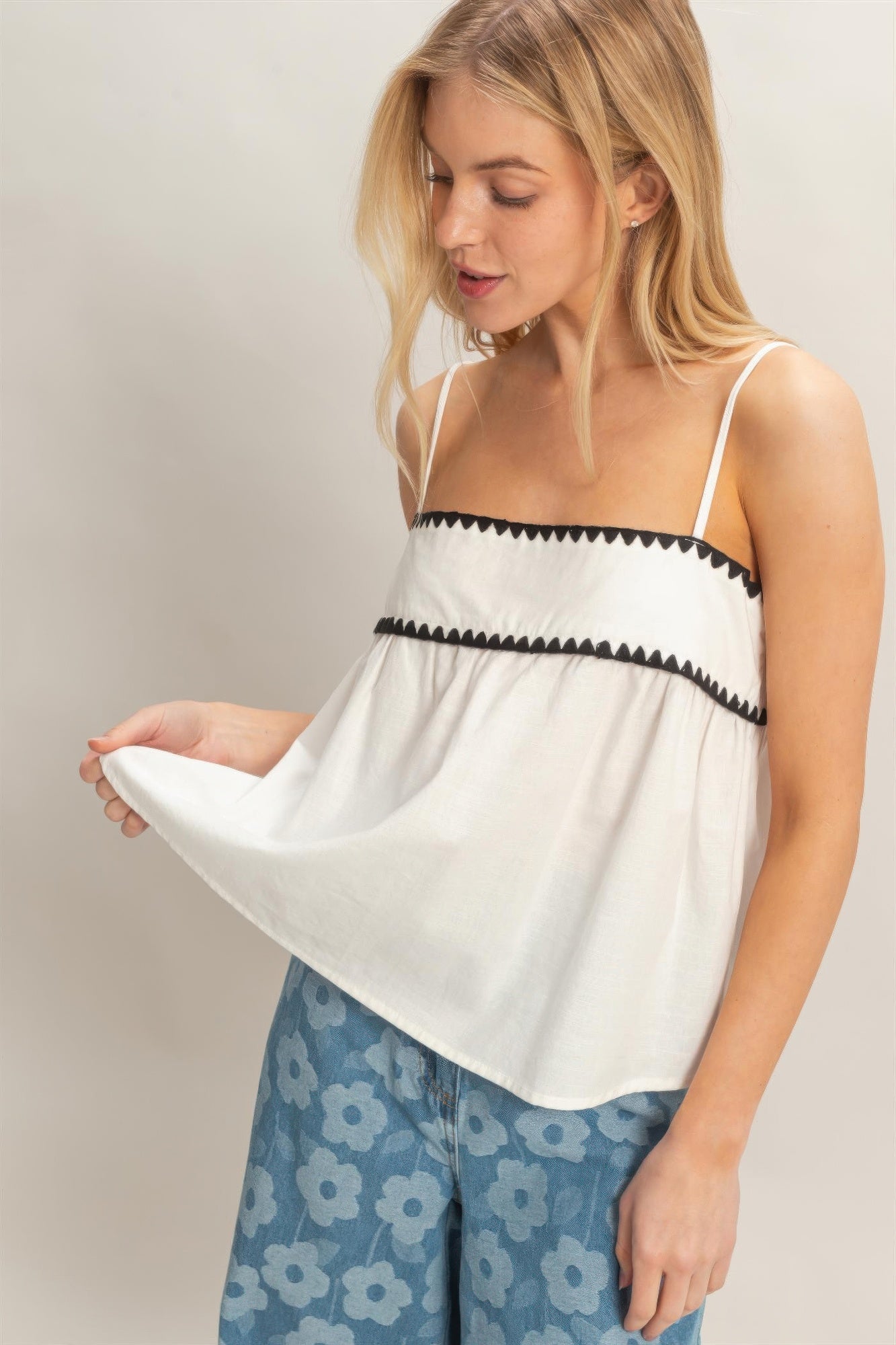 Haut babydoll blanc sans manches, bretelles fines et volants avec liseré noir.